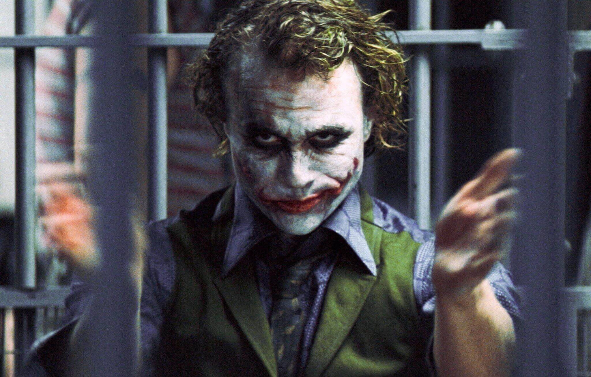 Why So Serious Joker 桌布 壁紙 — 小丑身穿綠色背心，臉上塗著白色顏料，隔著監獄鐵欄露出狂笑。
