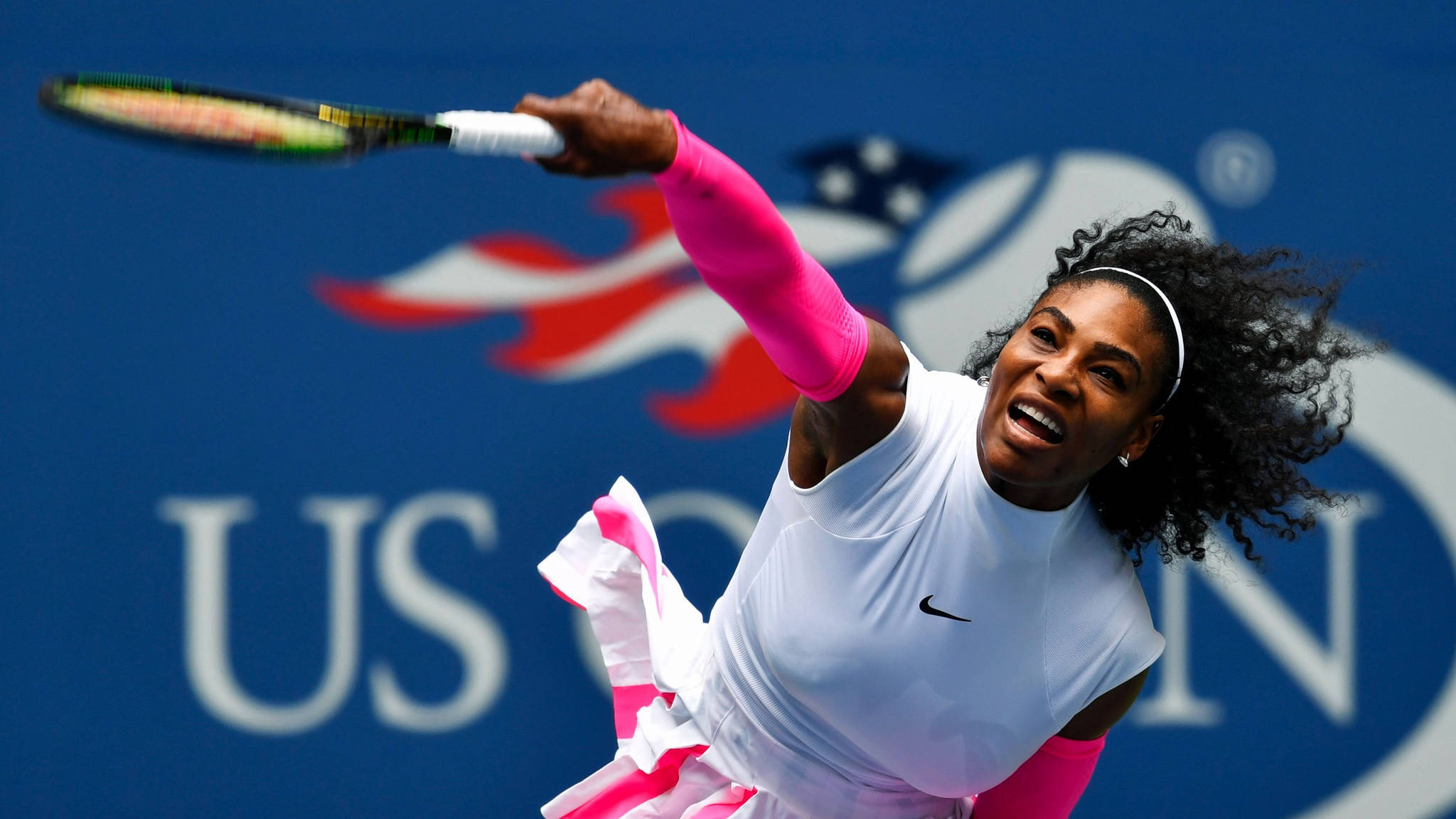 Serena 桌布 壁紙 — 小威廉絲以白色和粉紅色裝束在藍色美國公開賽背景下強力揮拍。