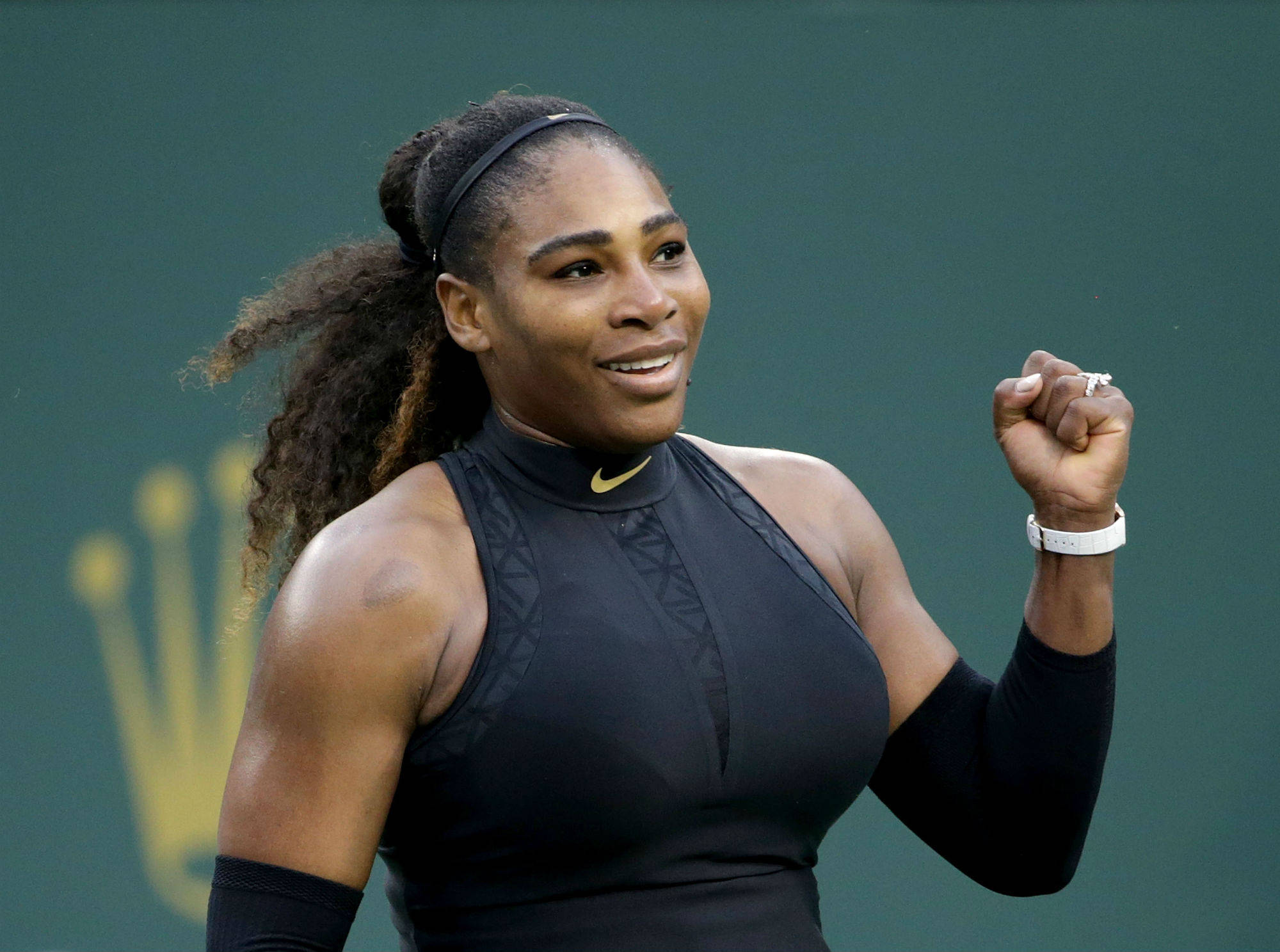 Serena 桌布 壁紙 — 小威廉絲在網球場上握緊拳頭，露出燦爛笑容，慶祝勝利。
