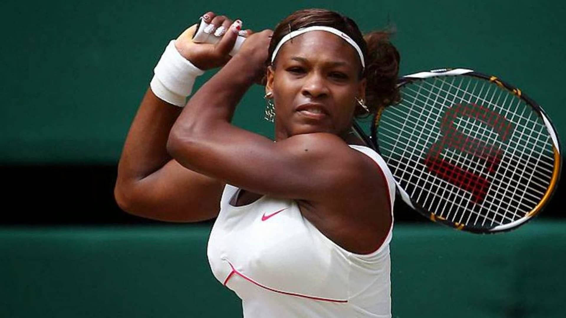 Serena 桌布 壁紙 — 小威廉絲在網球比賽中揮拍，身穿白色運動裝備，背景為綠色球場。