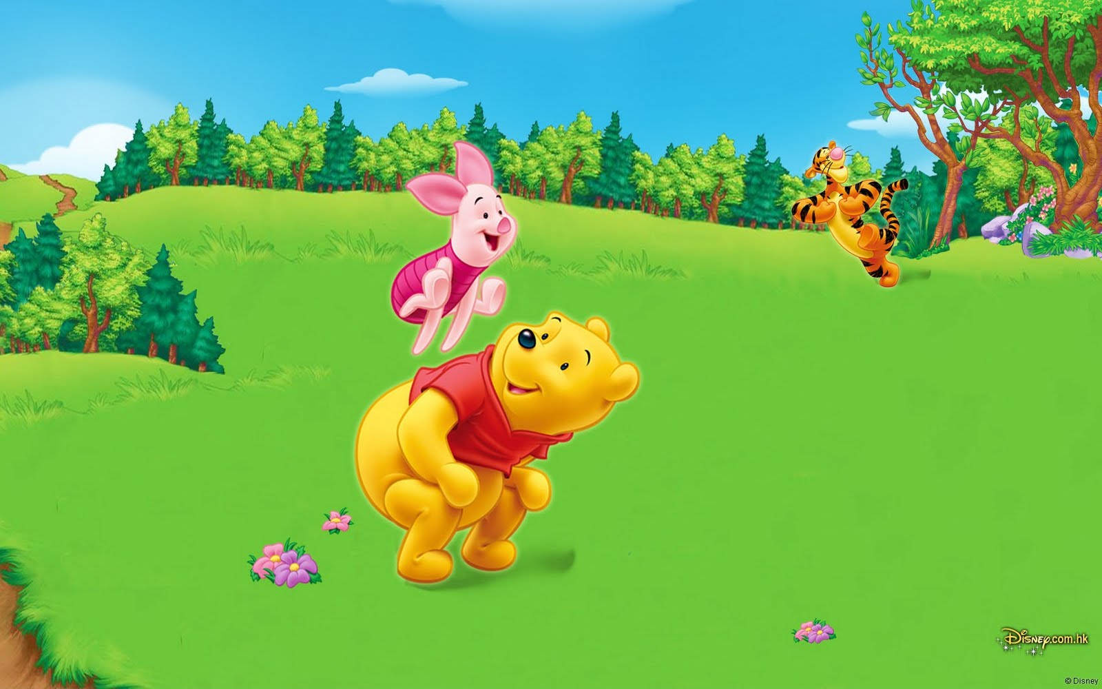 winnie the pooh 桌布 壁紙 — 小熊維尼在晴朗的藍天下，開心地抱著小豬，穿過一片充滿活力的綠色草地，跳跳虎在附近跳來跳去。