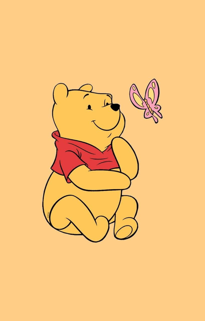 小熊維尼微笑，一隻粉紅色蝴蝶在桃色背景上靠近他飛翔。 — Winnie the pooh GIF 壁紙