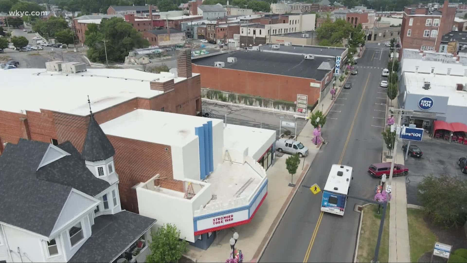 Ashland County 桌布 壁紙 — 小鎮街道的鳥瞰圖，有磚砌建築、白色教堂和一輛巴士駛過商店門面。