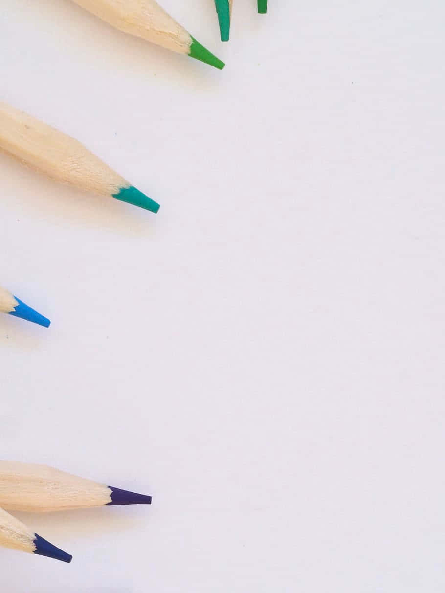 pencil 桌布 壁紙 — 尖銳的彩色鉛筆，帶有綠色、藍色和黑色筆尖，對角排列在乾淨的白色表面上。