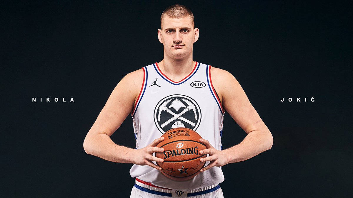 Jokic 桌布 壁紙 — 尼古拉·約基奇自信地站立，手持一個Spalding籃球，身穿白色全明星球衣，背景為深色攝影棚。