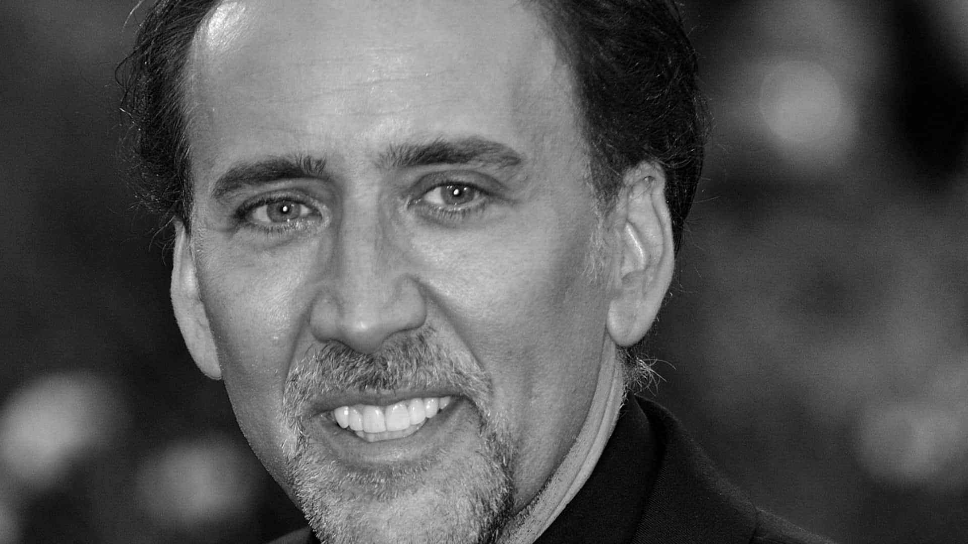 Celebrity 桌布 壁紙 — 尼可拉斯凱吉的黑白特寫肖像，他溫暖地微笑，焦點清晰落在他充滿表情的眼睛和鬍鬚上。