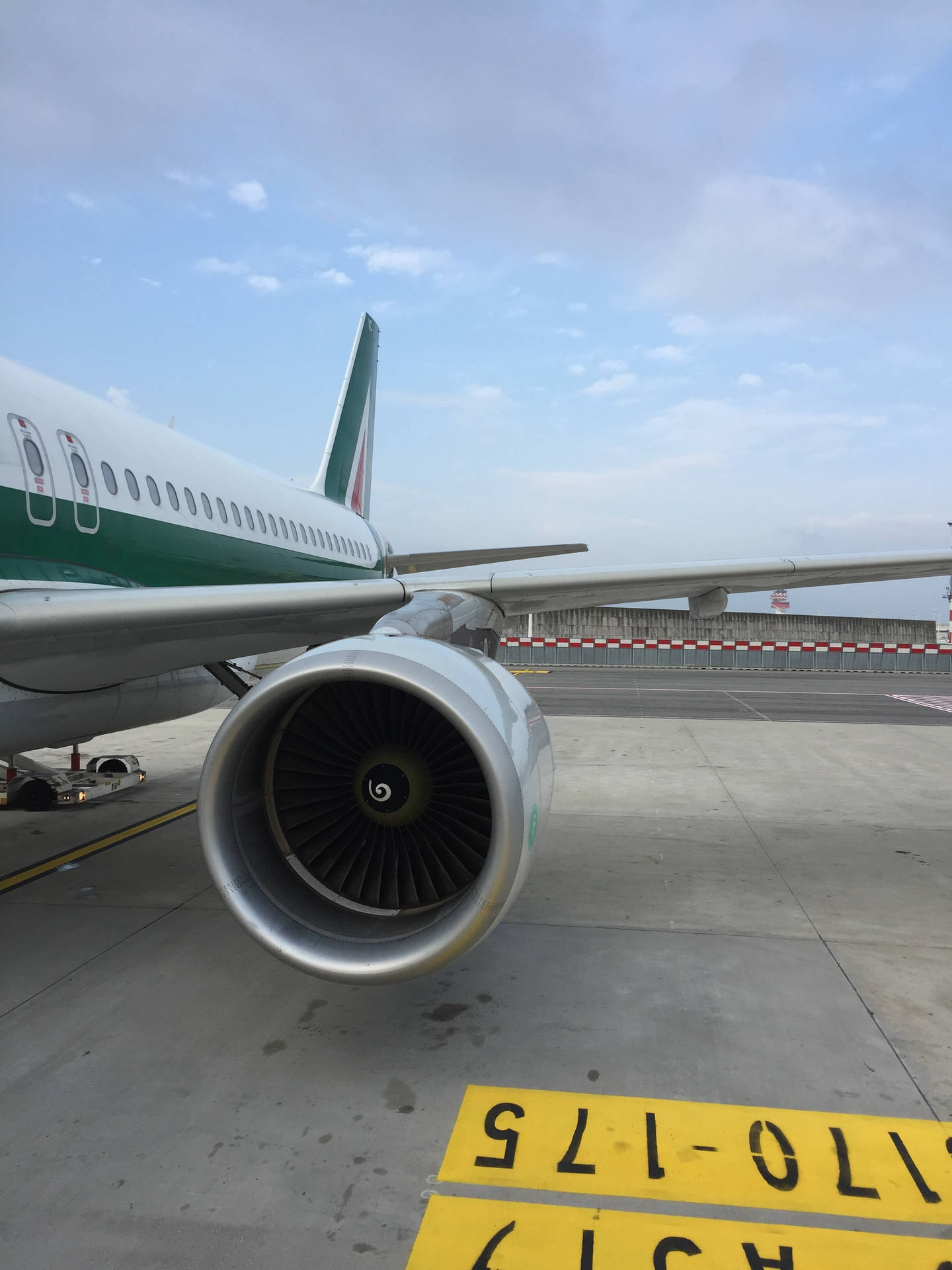 壁紙 — 局部多雲天空下，停機坪上綠色和白色飛機引擎的特寫。