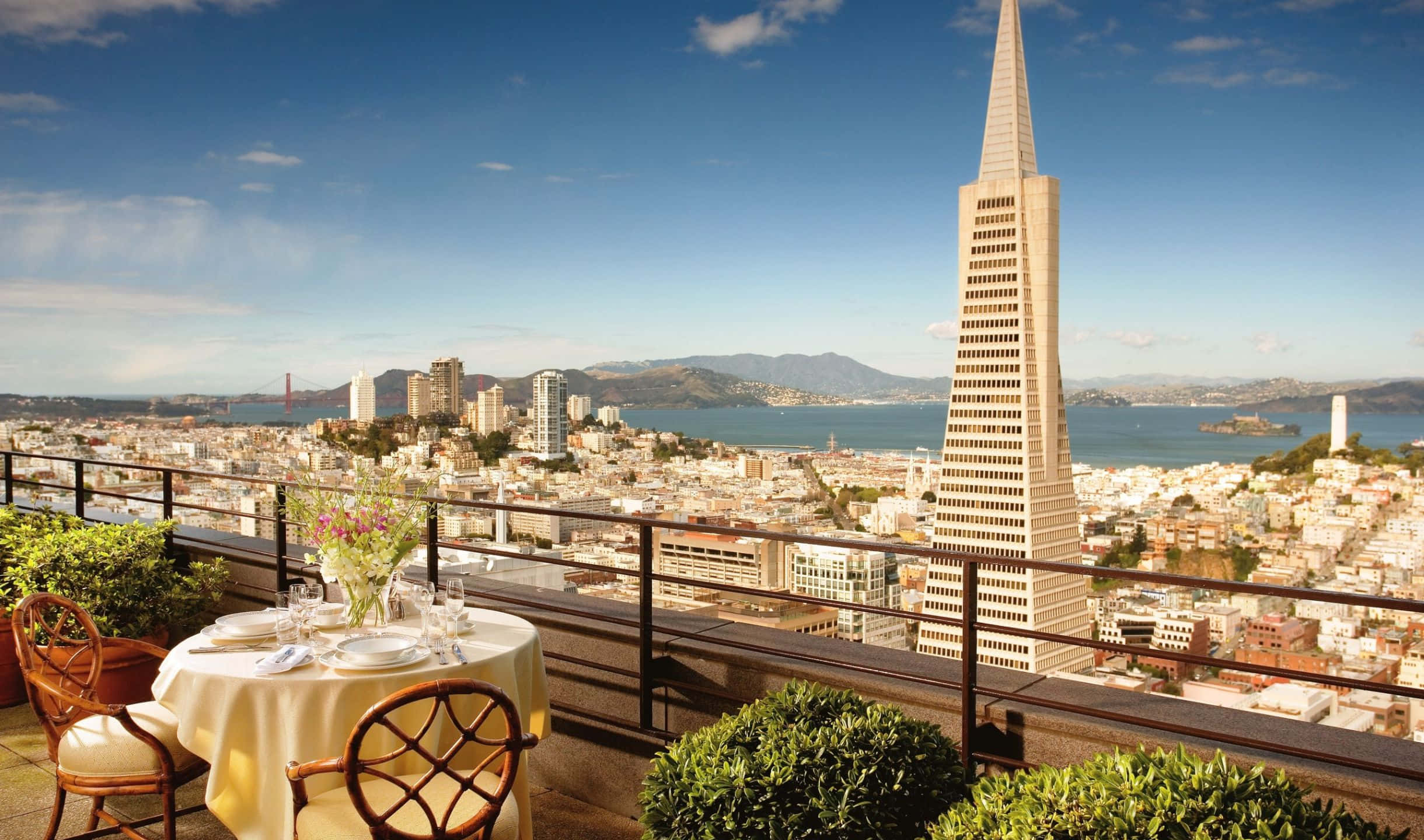 2440x1440 San Francisco 桌布 壁紙 — 屋頂用餐餐桌俯瞰舊金山標誌性的泛美金字塔和金門大橋，在清澈的藍天下。