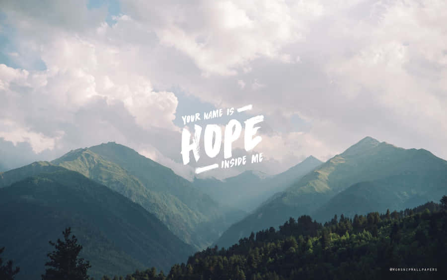 Aesthetic Tumblr Desktop 桌布 壁紙 — 山脈在陰天天空下，白色文字 'YOUR NAME IS HOPE INSIDE ME' 疊加在上面。