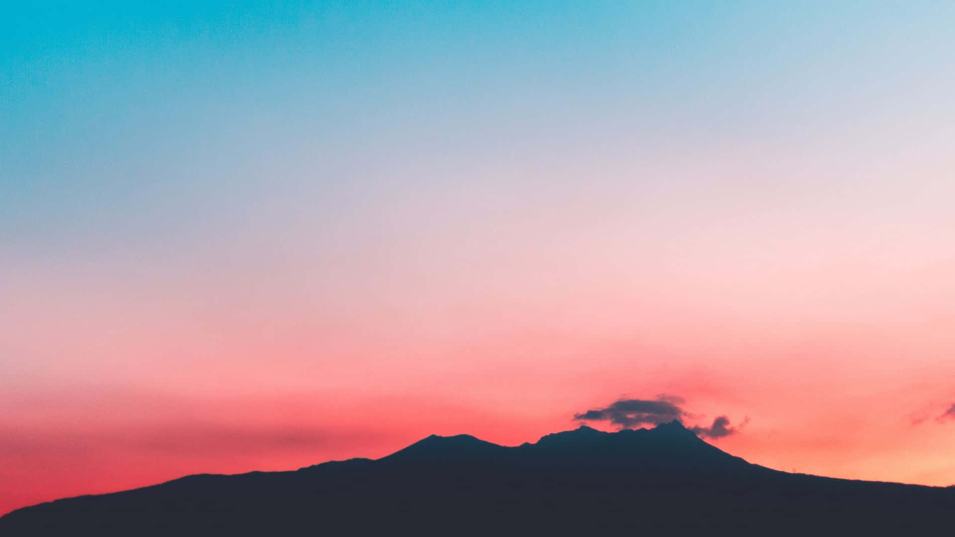 夕陽天空 桌布 壁紙 — 山脈的剪影，映襯著充滿活力的粉紅色和藍色日落天空，伴隨著縷縷薄雲。