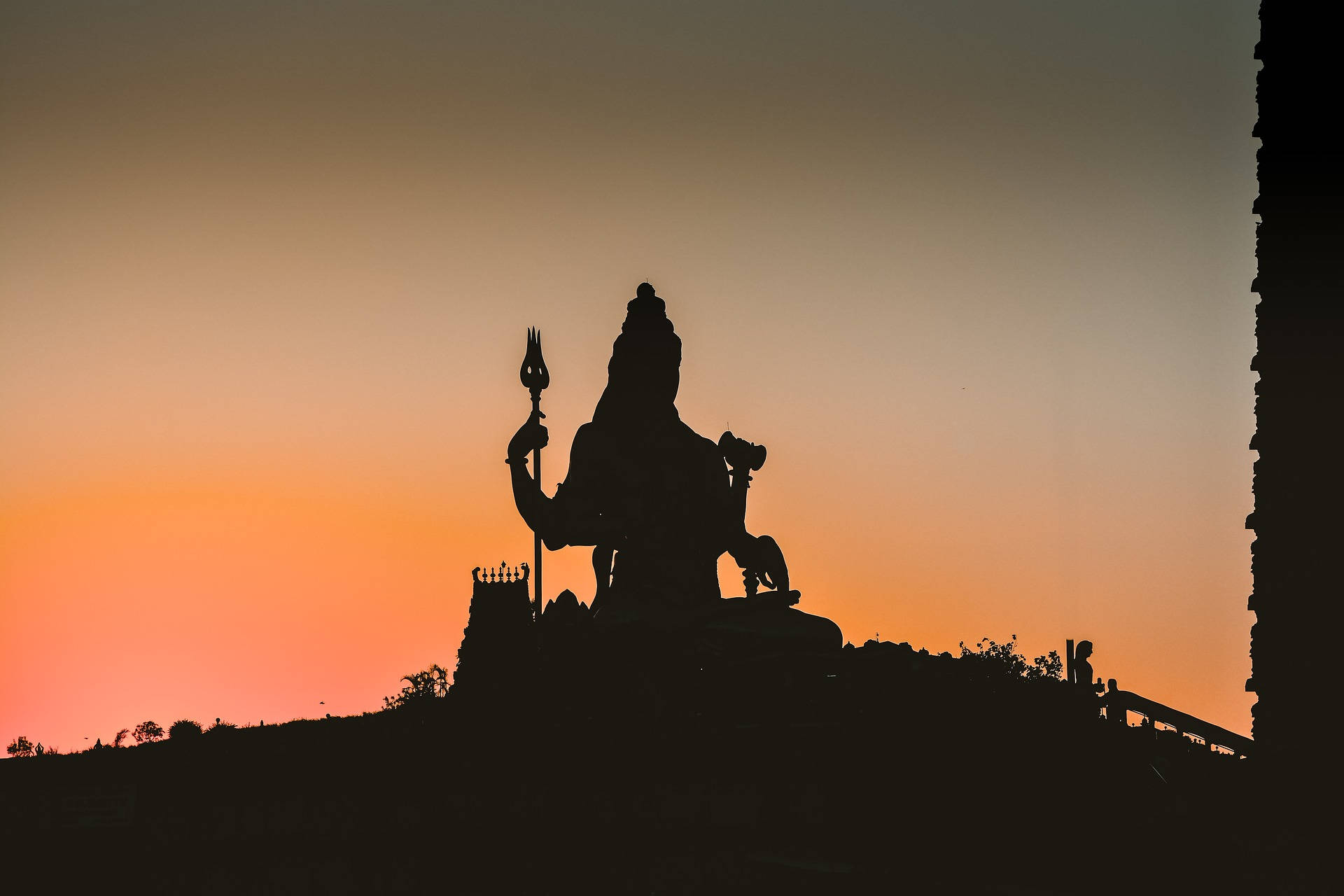 shiv shankar 桌布 壁紙 — 山頂上印度教神像的剪影，襯著充滿活力的橙粉紅色日落天空。