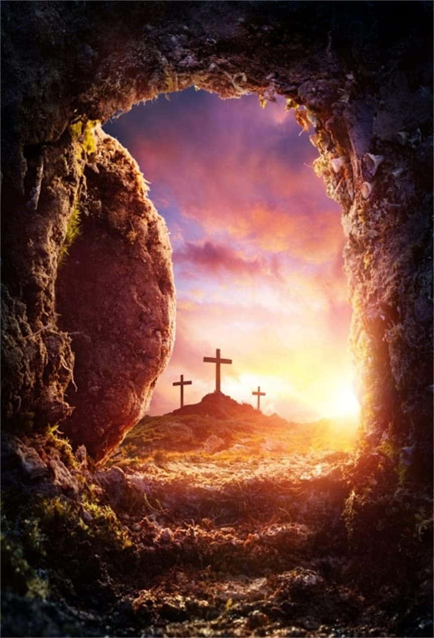 Empty Tomb 桌布 壁紙 — 岩石墓穴入口框住三個十字架，在 vibrant 的日落天空下呈現剪影。
