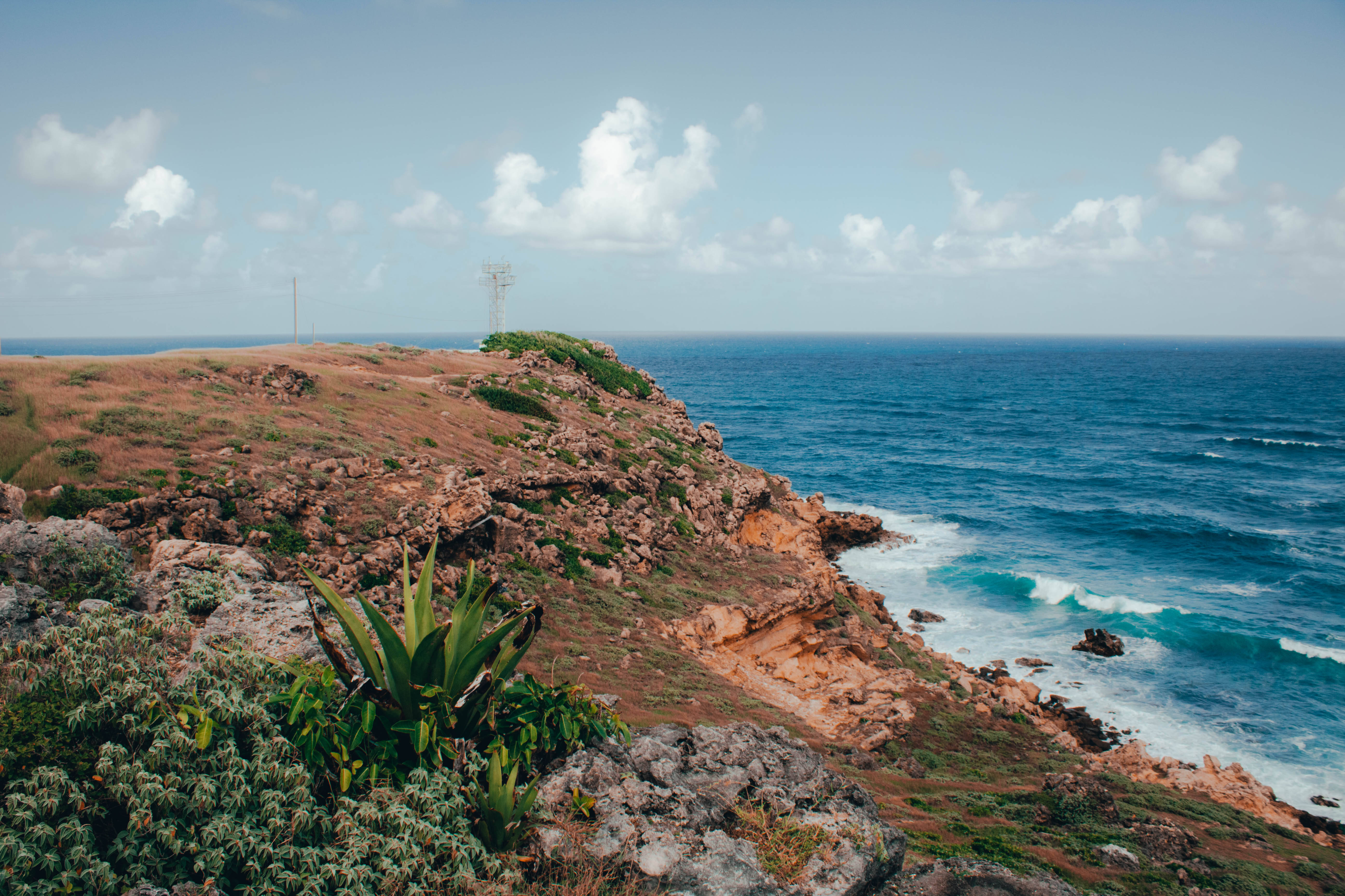 Barbados 桌布 壁紙 — 崎嶇的海岸懸崖，在部分多雲的天空下，碧綠色的海浪拍打岩石。