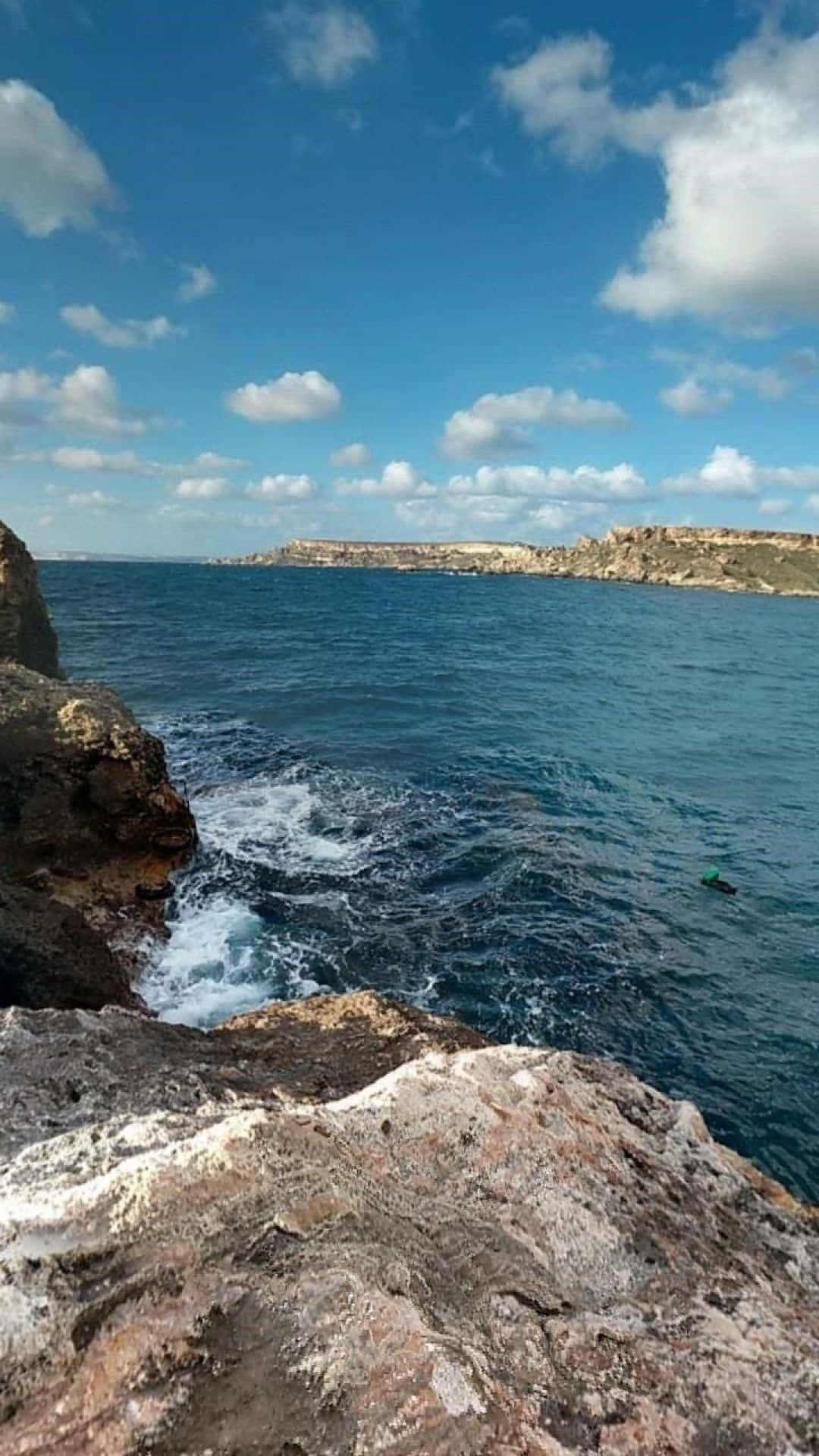 Panorama 桌布 壁紙 — 崎嶇的海岸懸崖在晴朗的天空下與深藍色的海洋相遇，天空中有散落的雲朵。