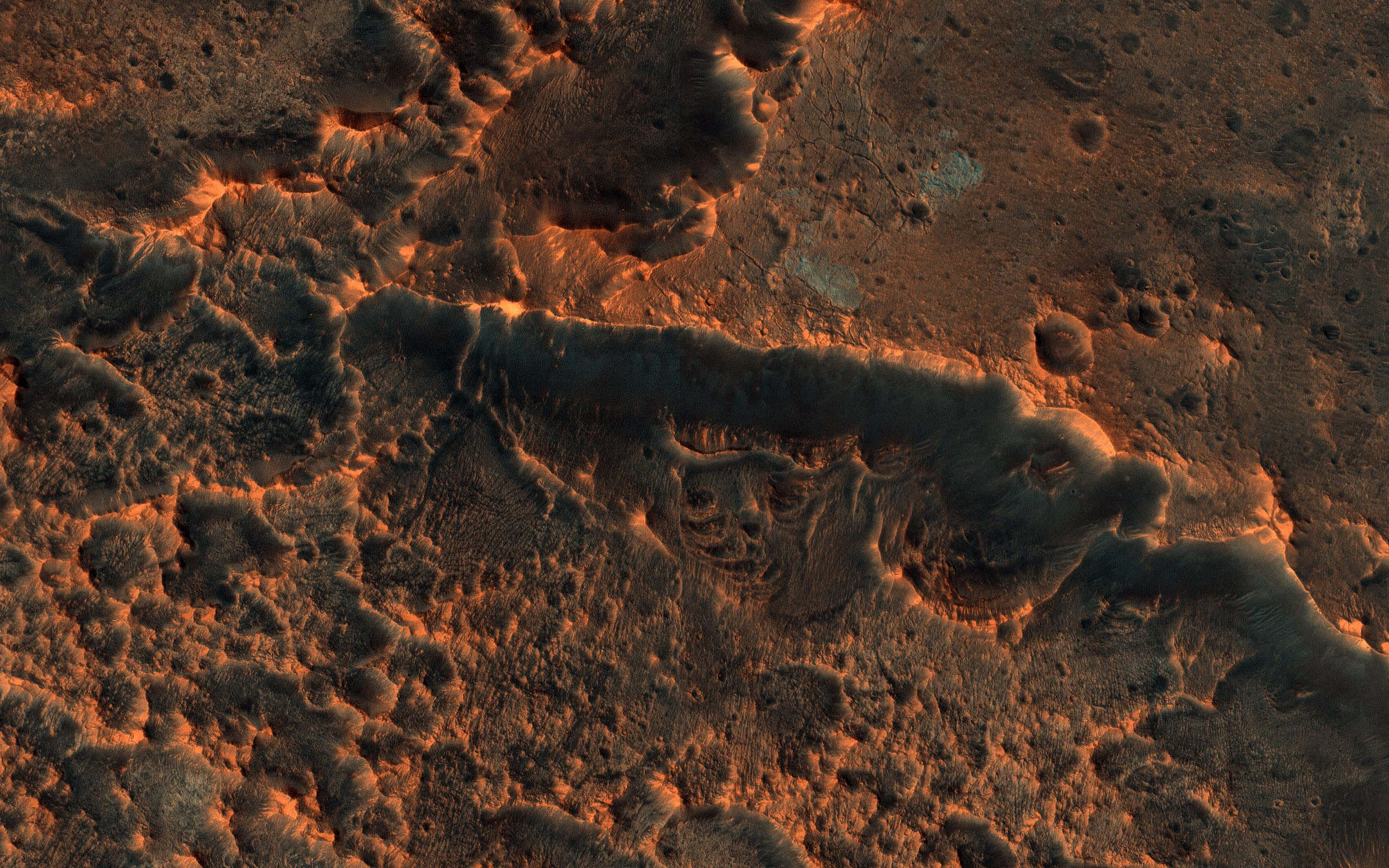 Mars Surface 桌布 壁紙 — 崎嶇的火星景觀沐浴在溫暖的橙色光線中，在荒涼的天空下呈現出紋理岩石結構和隕石坑。