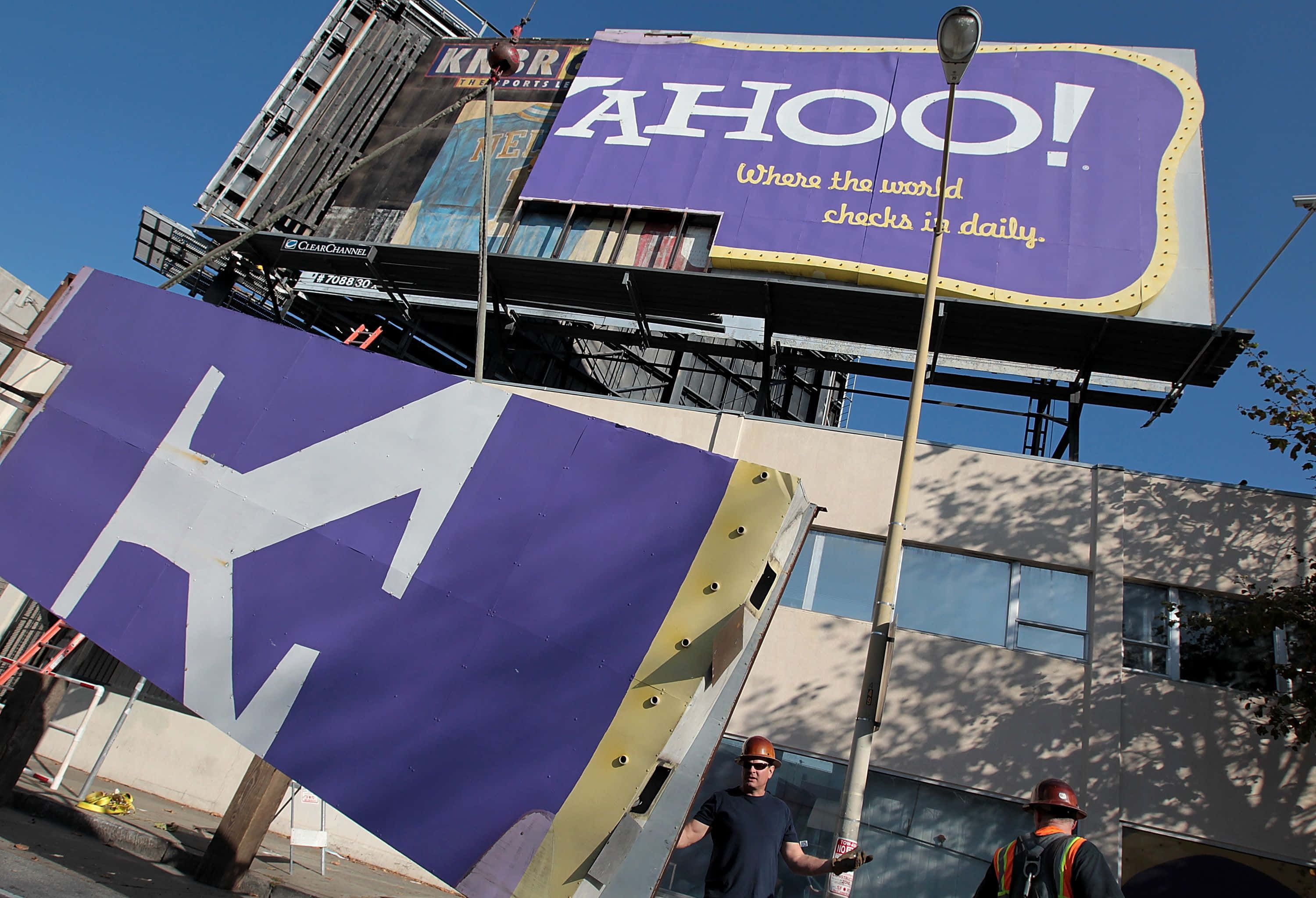 Yahoo 桌布 壁紙 — 工人正在晴朗的藍天下安裝一個帶有白色字體的紫色Yahoo!大型廣告牌。