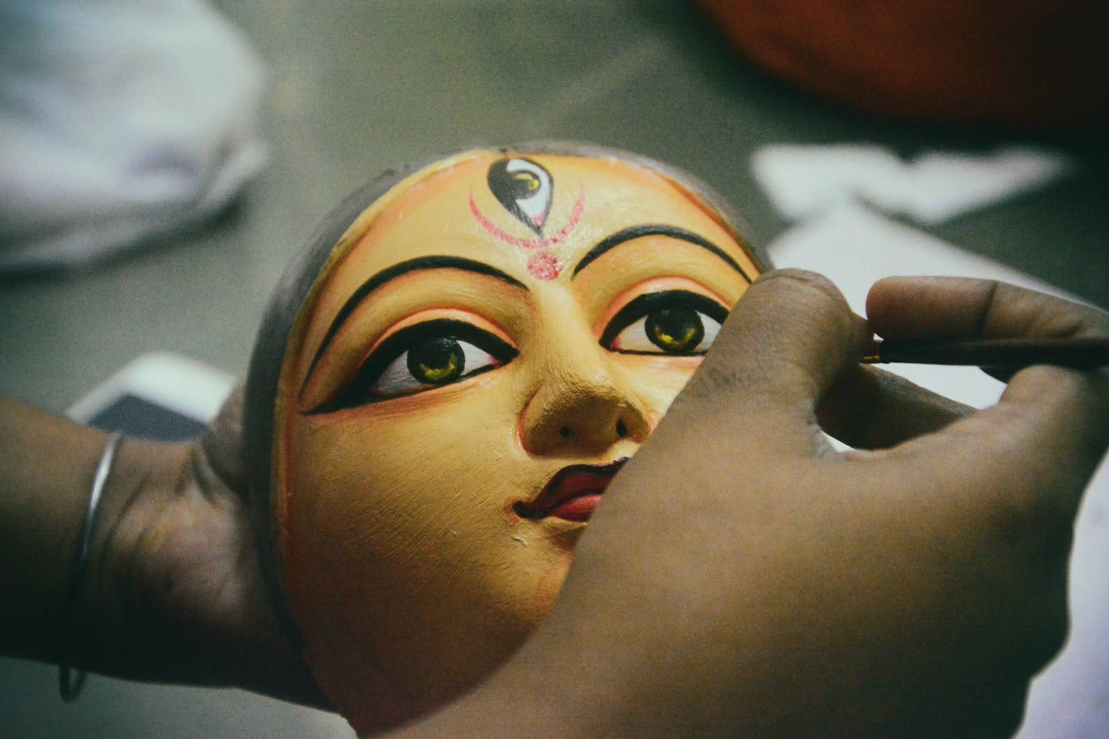 maa durga 桌布 壁紙 — 工匠用細筆精心繪製傳統印度神祇面具上的複雜細節。