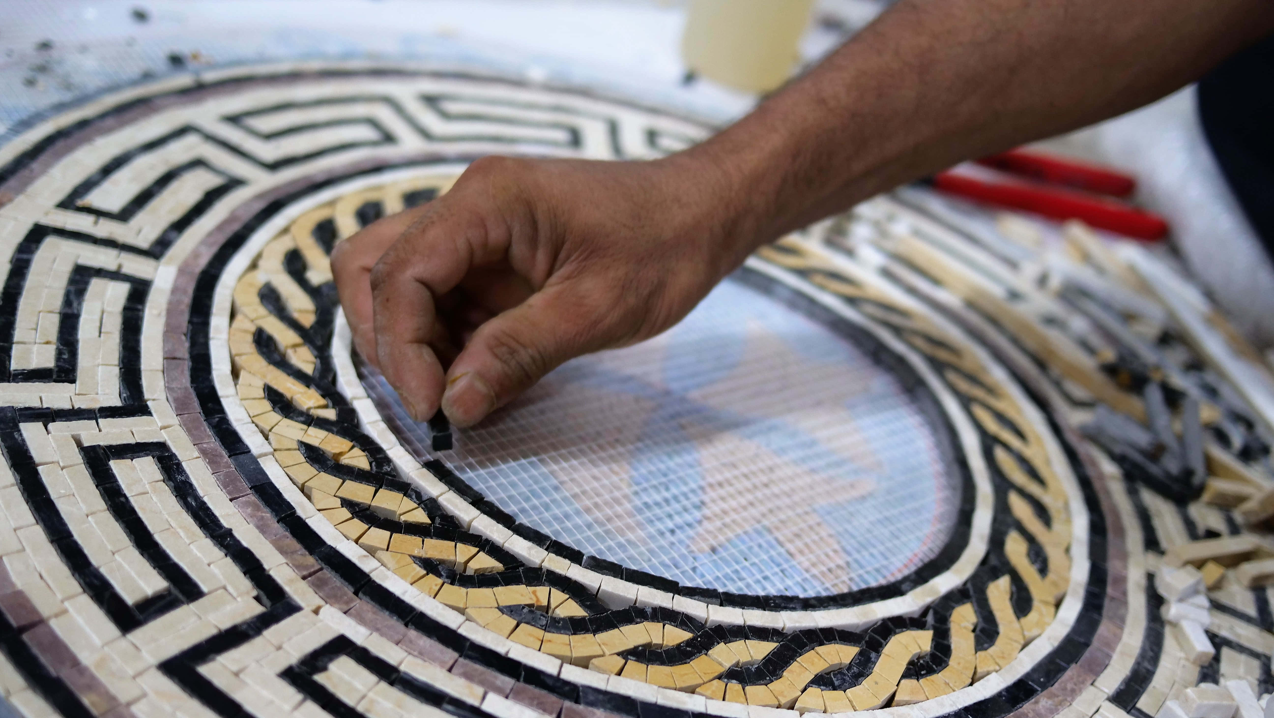 Mosaic 桌布 壁紙 — 工匠的手將一塊小瓷磚放入一個帶有黑色、米色和白色圖案的圓形幾何馬賽克中。