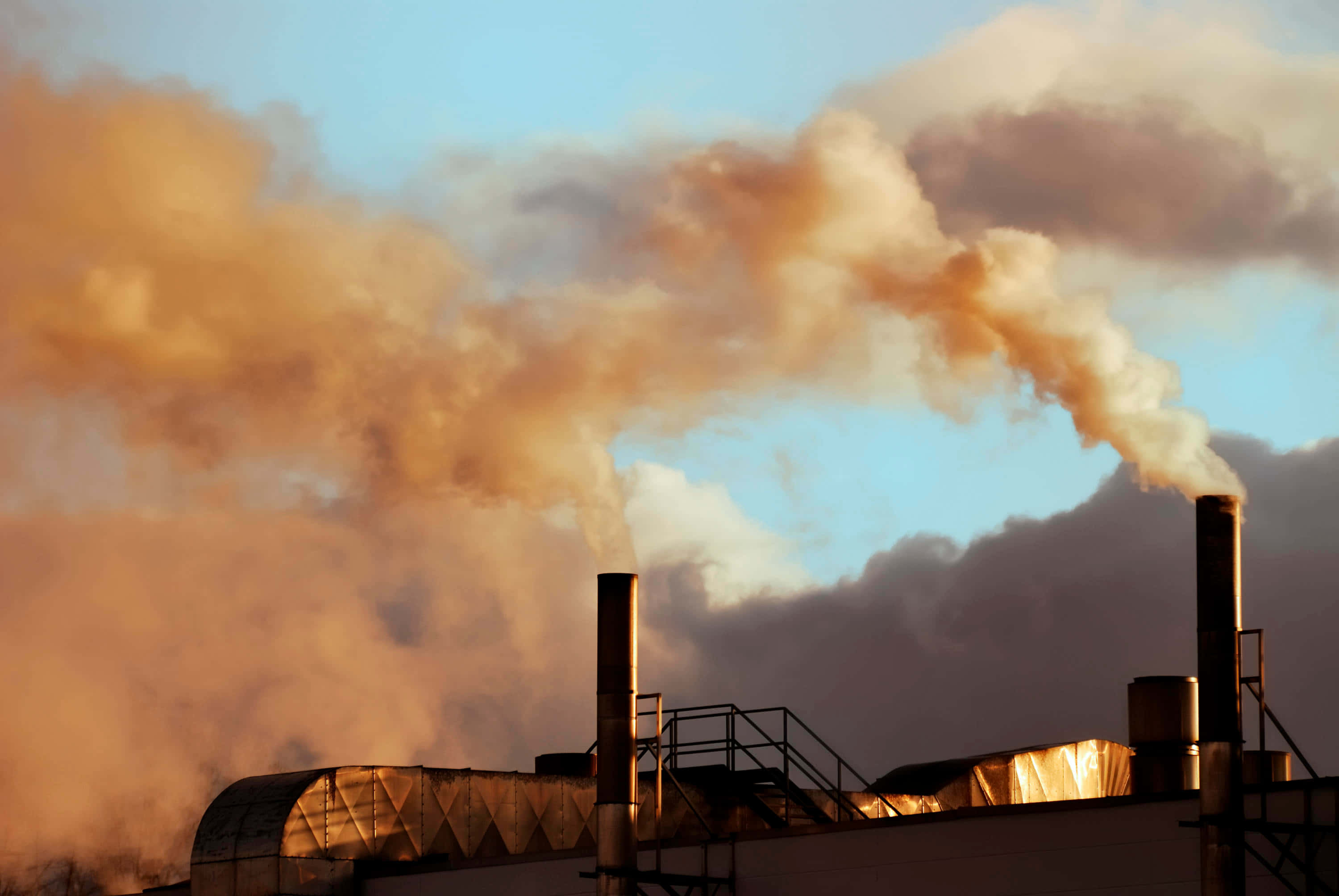 Pollution 桌布 壁紙 — 工廠煙囪排放的工業煙霧，在帶有溫暖橙色和藍色色調的暮色天空中翻騰。