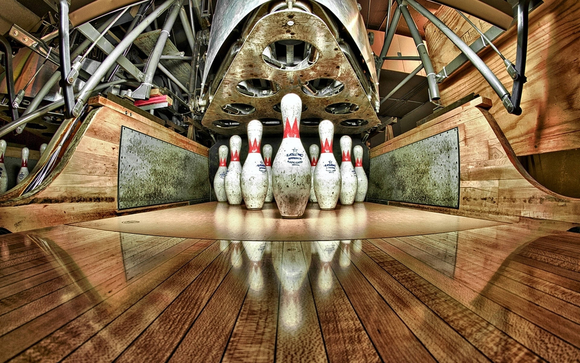 Bowling 桌布 壁紙 — 工業機械下方，拋光木製球道上磨損的保齡球瓶的低角度視圖。