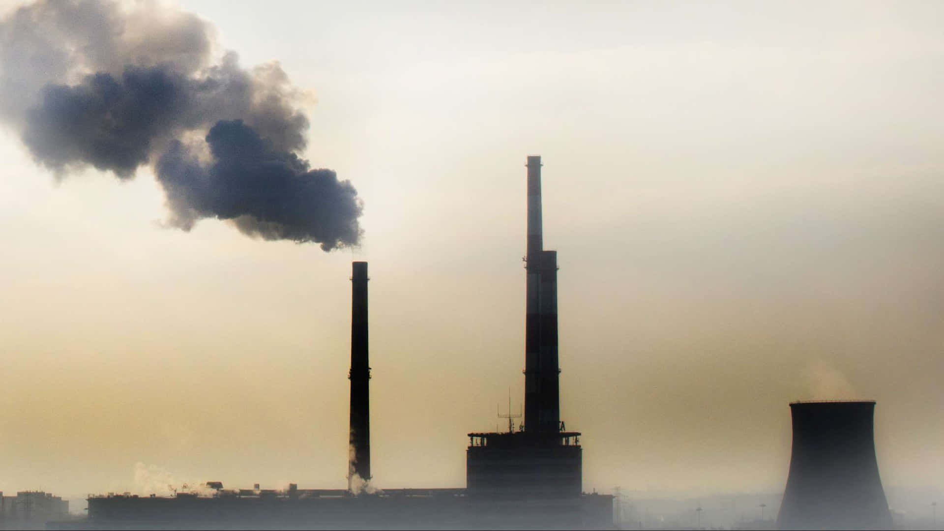 Pollution 桌布 壁紙 — 工業煙囪在黎明時分排放濃黑煙霧，映襯著朦朧的橙色天空。
