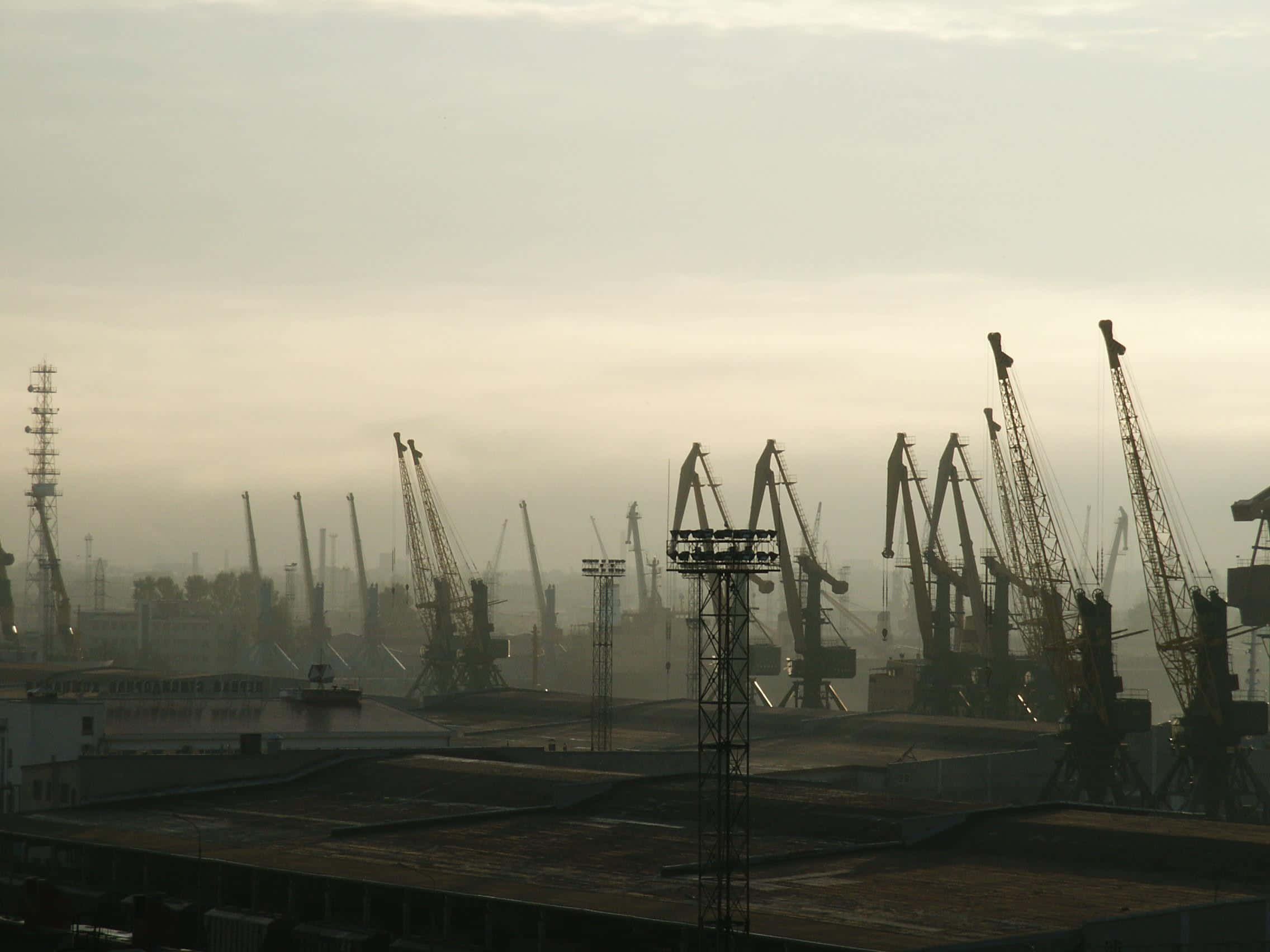 Dust 桌布 壁紙 — 工業起重機的剪影在寧靜港口上空朦朧的黎明天空中高高聳立。