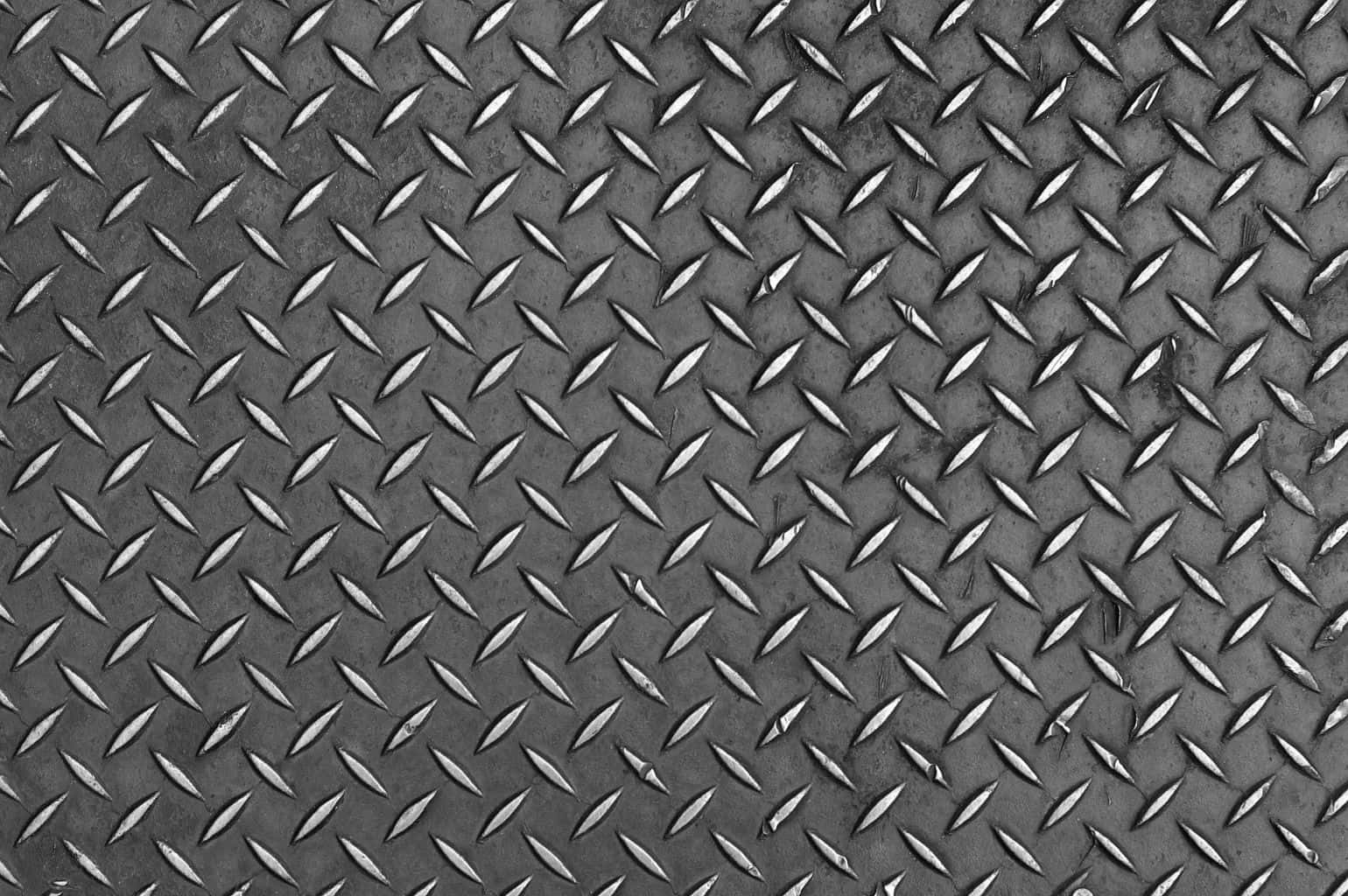 Diamond Plate 桌布 壁紙 — 工業鑽石板金屬的特寫，帶有重複的凸起鑽石圖案和微妙的表面磨損。