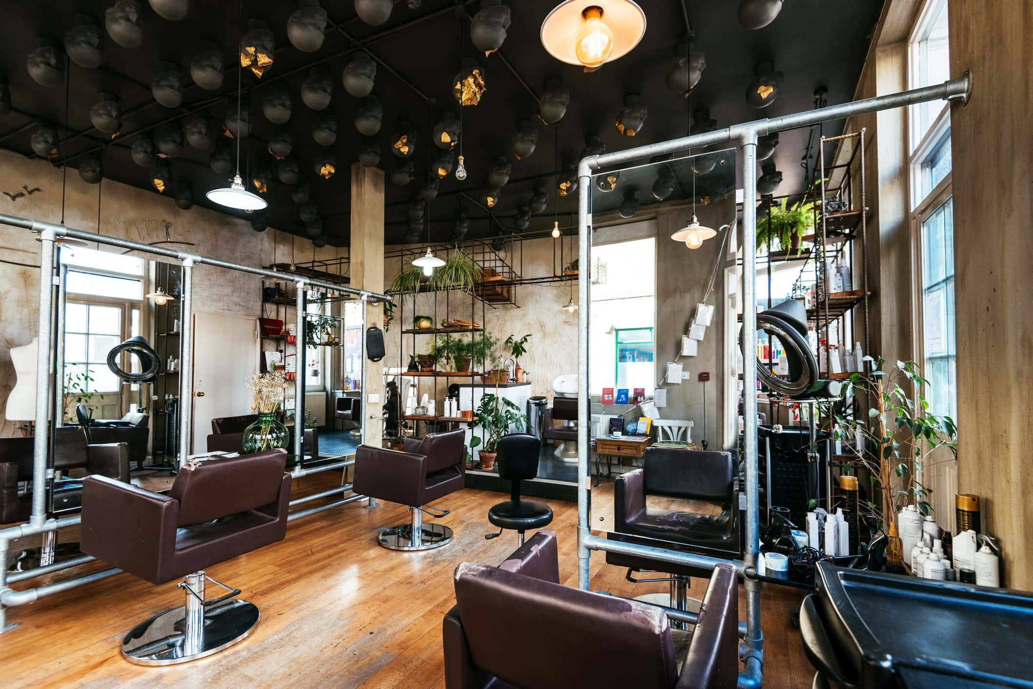 Hair Salon 桌布 壁紙 — 工業風時尚髮廊，配有外露管道、鏡子和吊燈，倒映在木地板上。