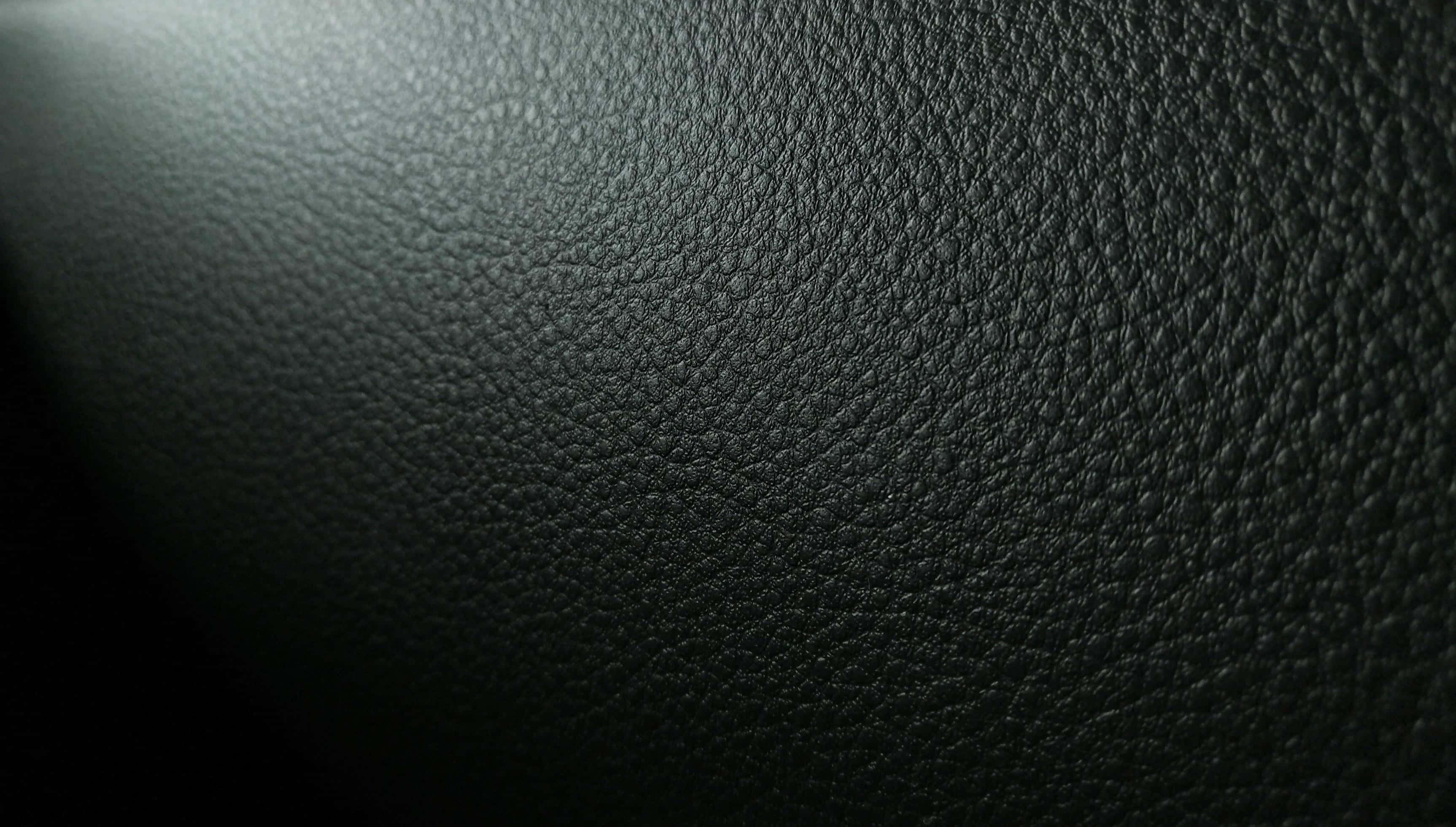 texture 桌布 壁紙 — 左上角柔和漸變燈光下的深色紋理皮革表面特寫。