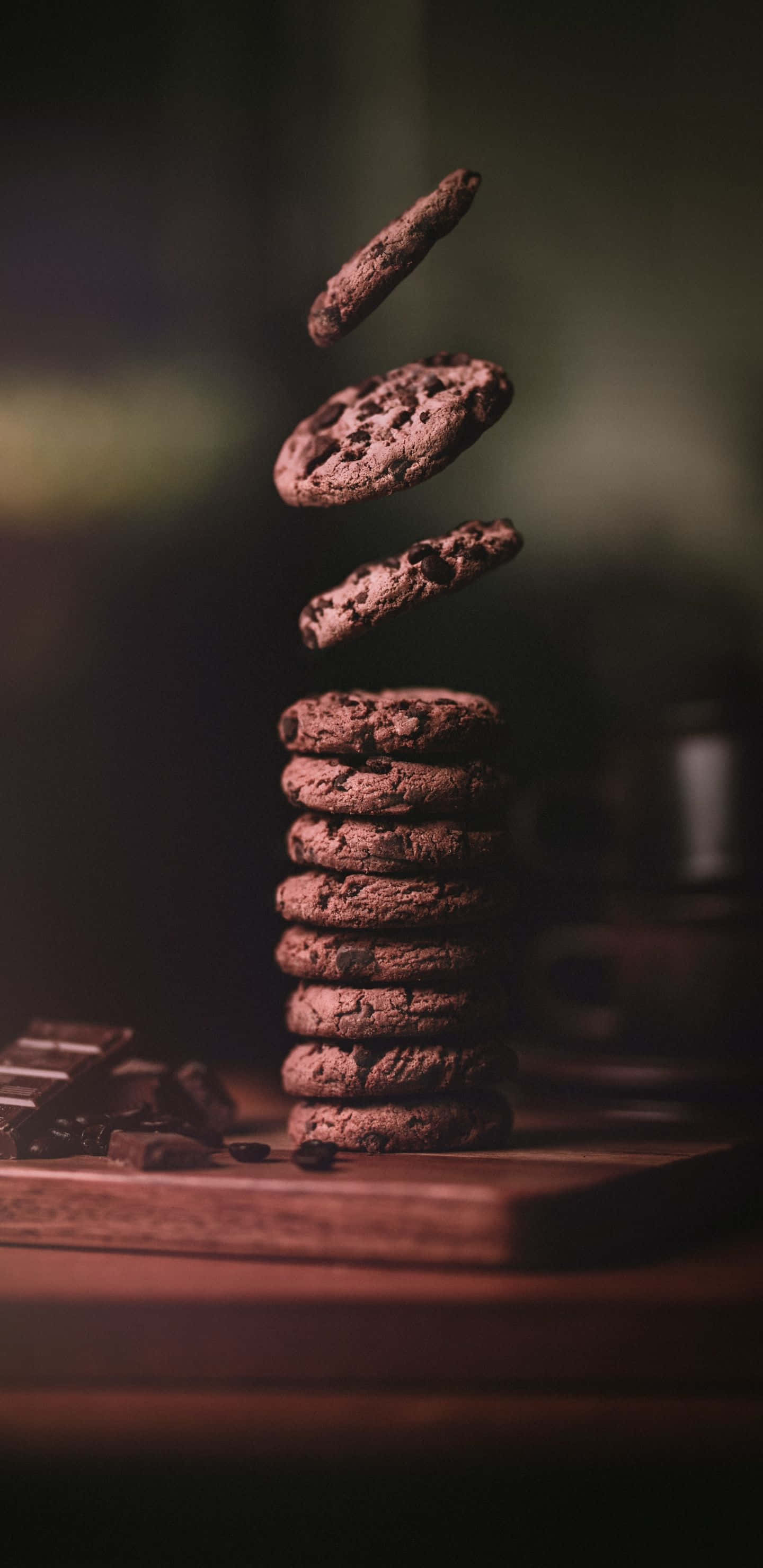 Pastry 桌布 壁紙 — 巧克力餅乾懸浮在空中，下方是木板上的一堆，溫暖昏暗的燈光。