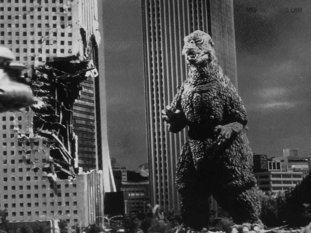 Godzilla 1954 桌布 壁紙 — 巨型怪獸哥吉拉站在黑白城市災難場景中破碎的摩天大樓之間。