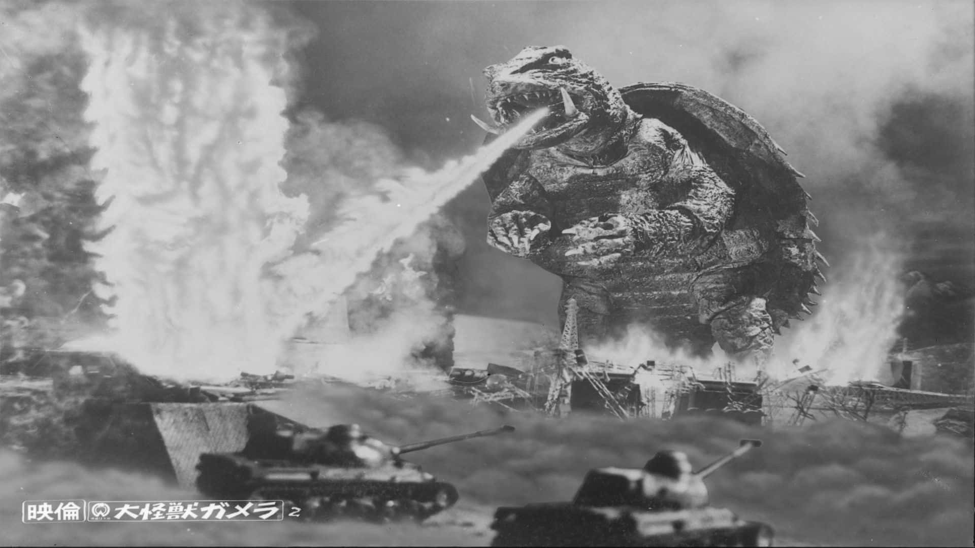 Gamera 桌布 壁紙 — 巨大的哥吉拉在燃燒的坦克和煙霧的戰場上釋放原子吐息。