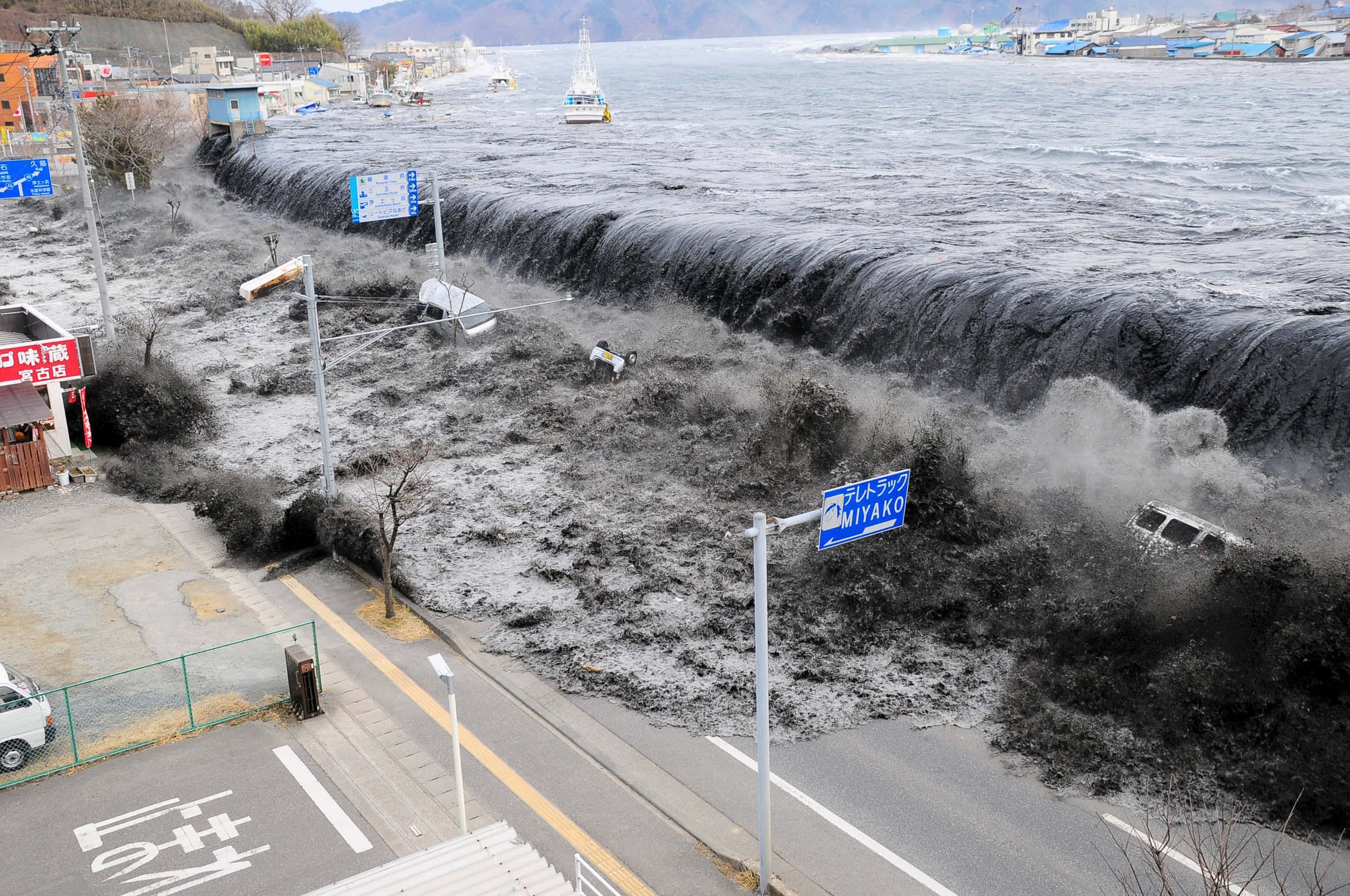 Tsunami 桌布 壁紙 — 巨大的海嘯席捲沿海城鎮，淹沒街道，沖走汽車和建築物。