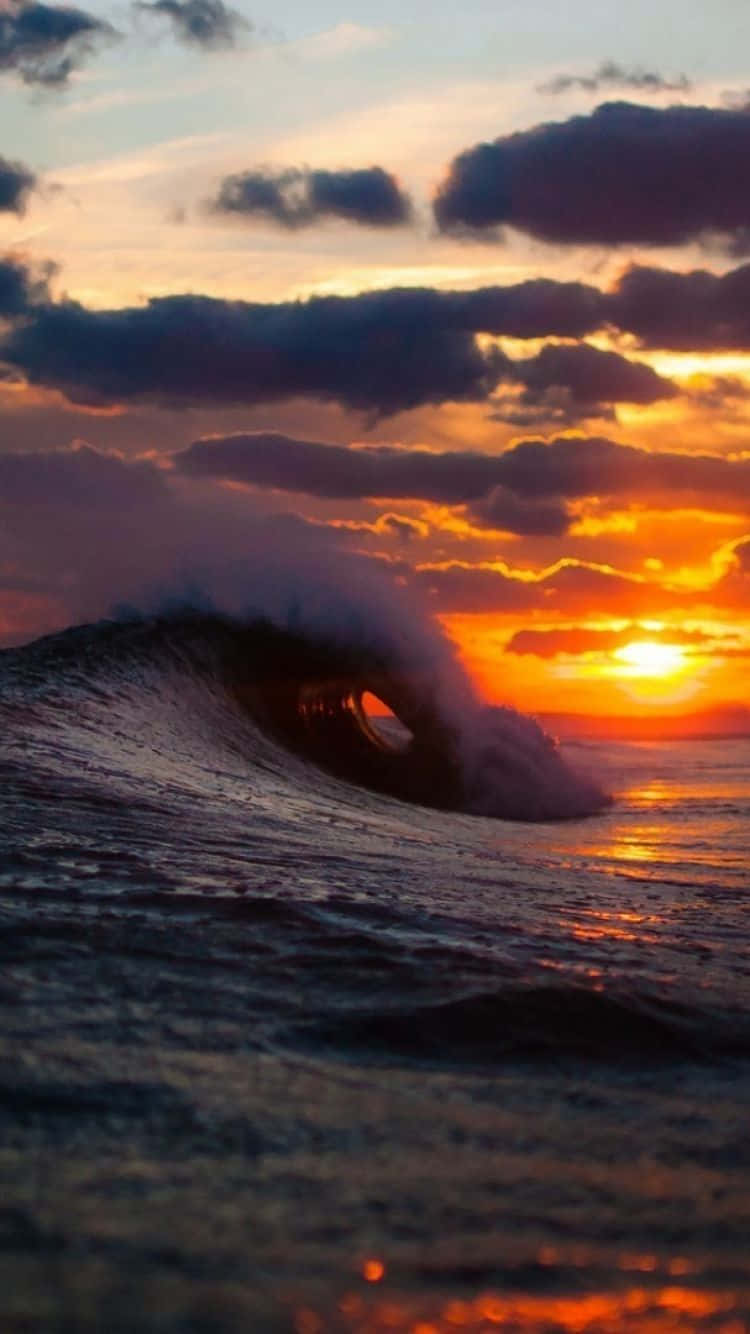 Surfing iPhone 桌布 壁紙 — 巨大的海浪在日落時捲成完美的管狀，上方有火橙色和紫色的雲彩。