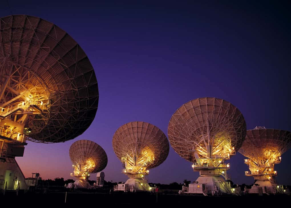 Radio Telescope 桌布 壁紙 — 巨大的無線電望遠鏡在深紫色暮色天空中溫暖地發光。