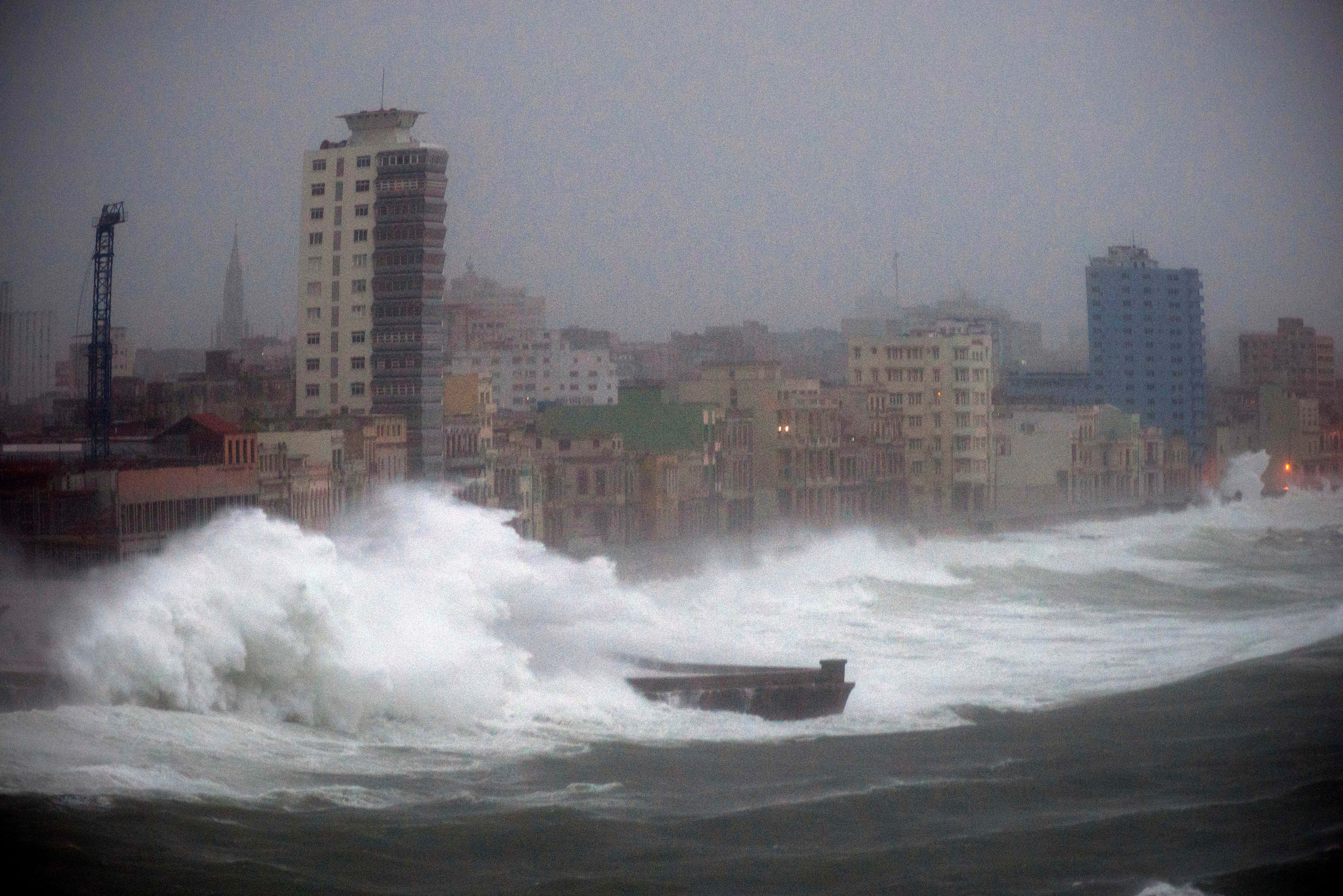 Hurricane 桌布 壁紙 — 巨大的破碎海浪吞噬了暴風雨灰色天空下的沿海城市景觀，建築物在薄霧中幾乎看不見。