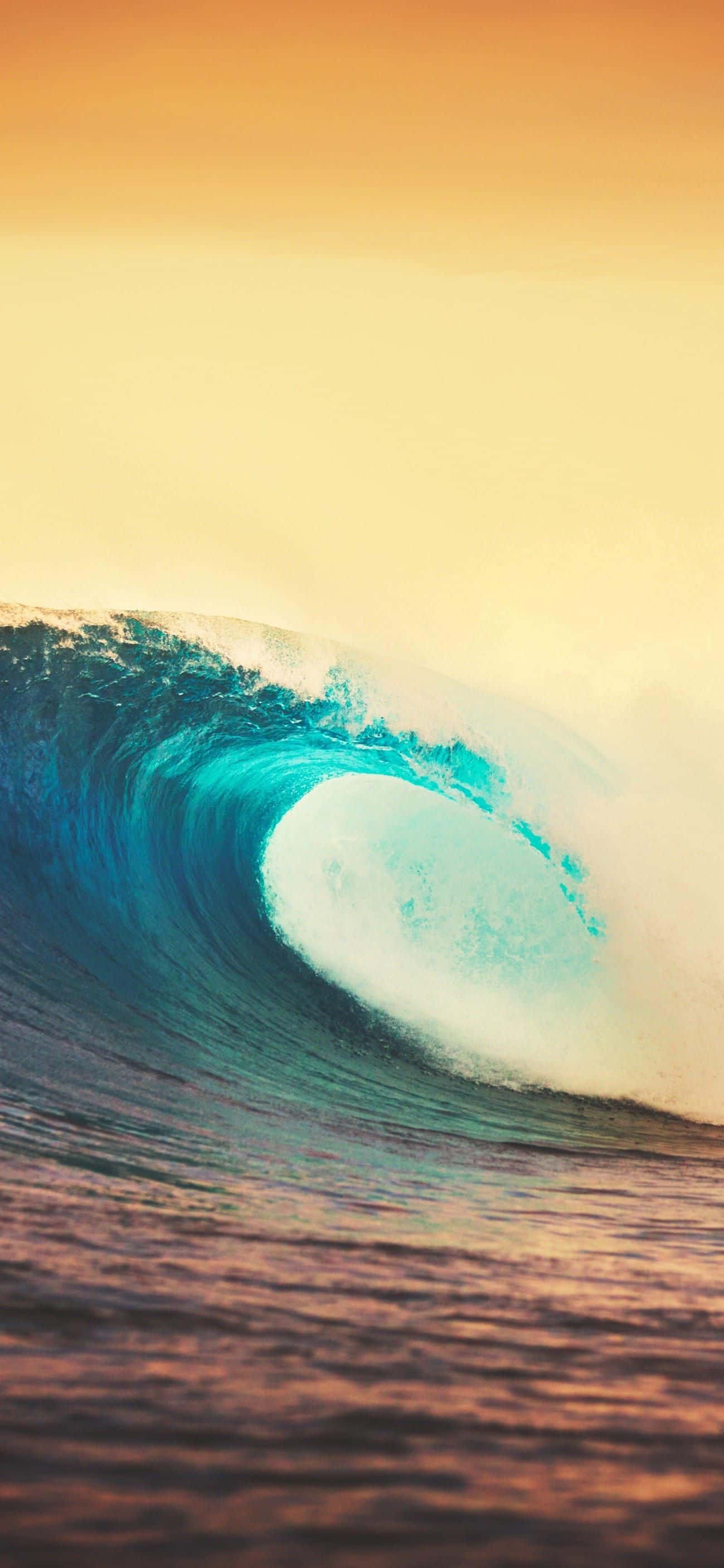 Surfing iPhone 桌布 壁紙 — 巨大的藍綠色海浪在溫暖的金色日落天空下捲成完美的桶狀。