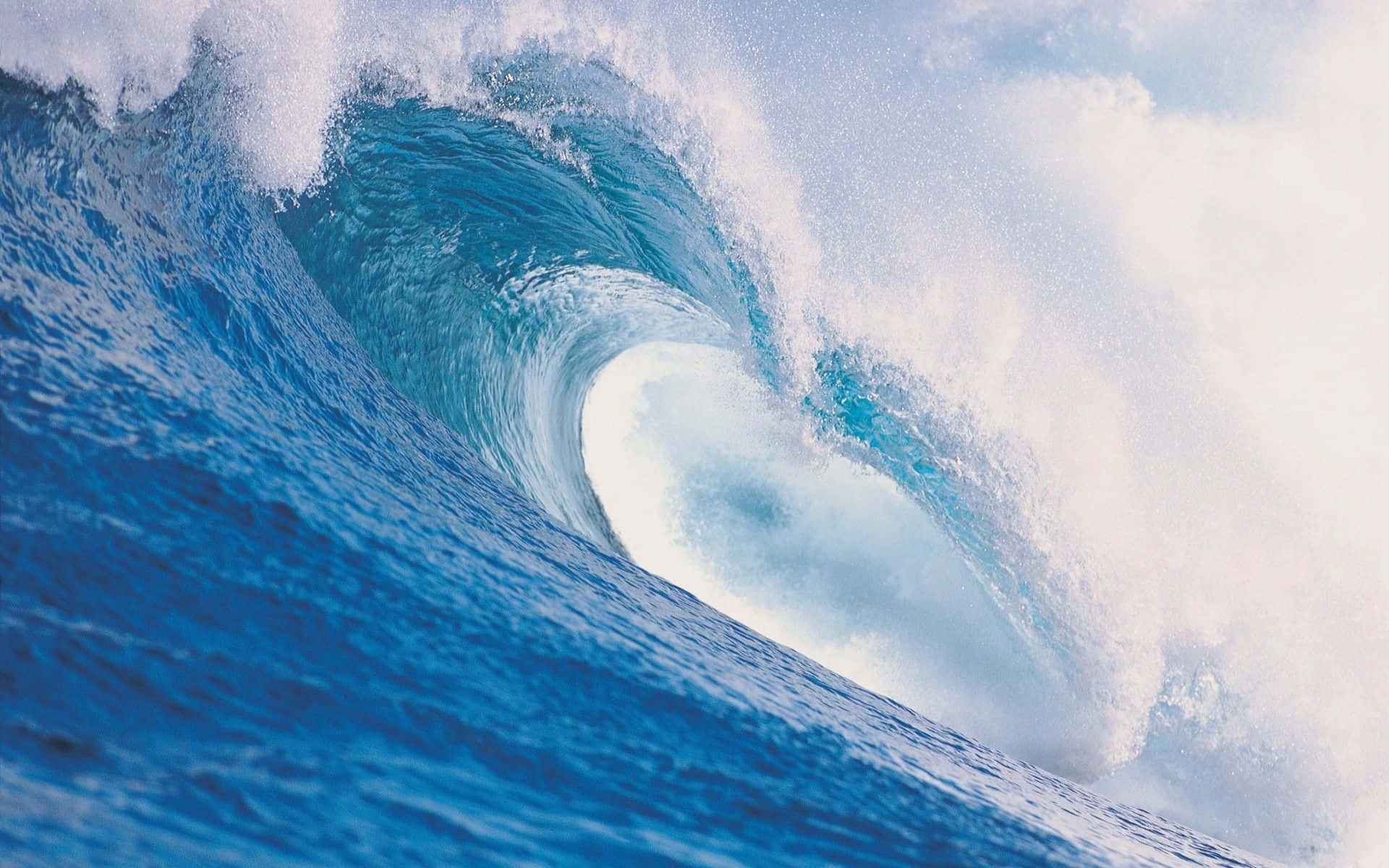 Ocean Waves 桌布 壁紙 — 巨大的藍綠色海浪捲成一個完美的筒狀，在明亮的天空下激起白色泡沫飛濺。