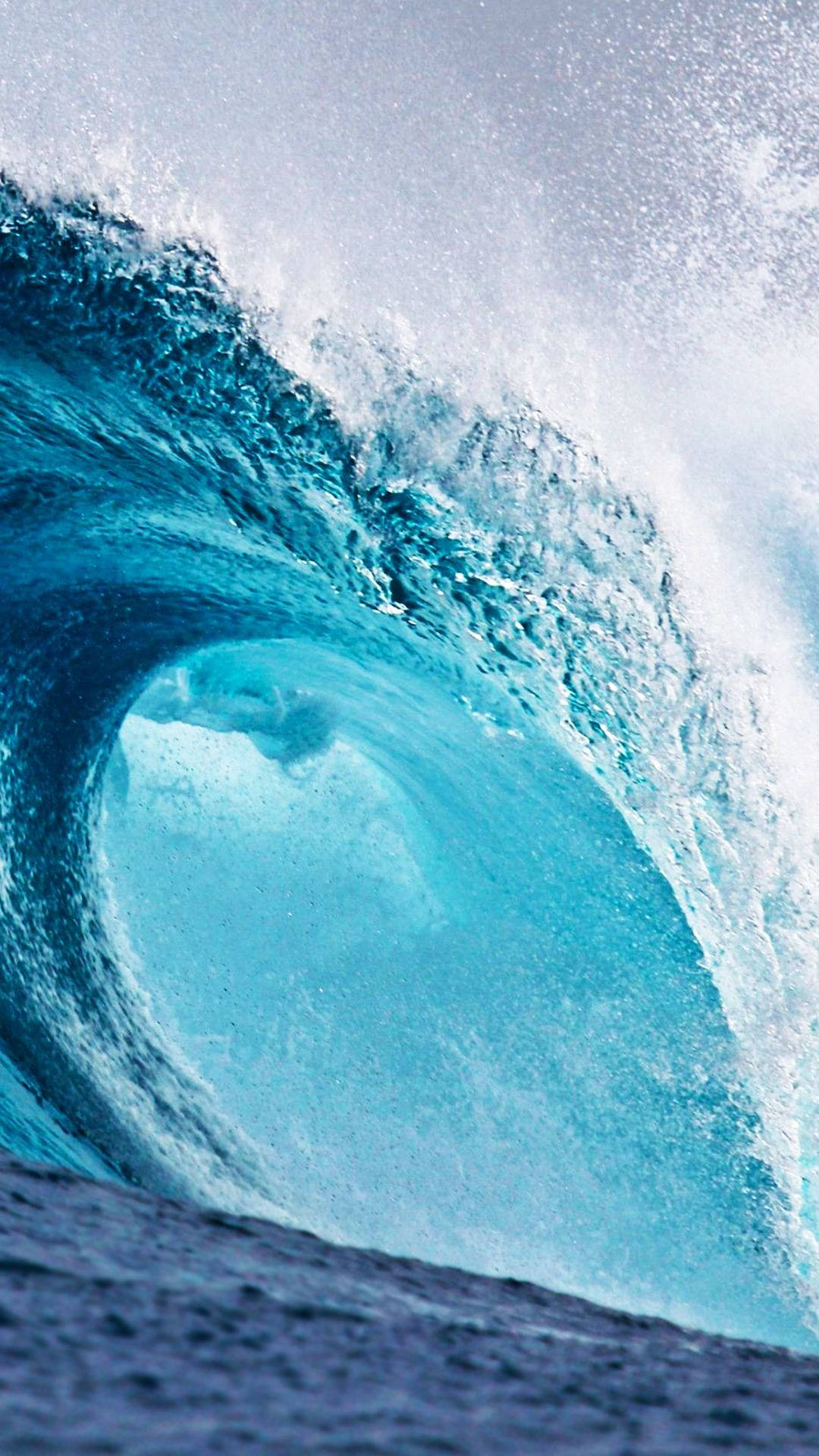Wave 桌布 壁紙 — 巨大的藍綠色海浪捲成完美的筒狀，帶著泡沫般的白色浪花，映襯著蒼白的天空。
