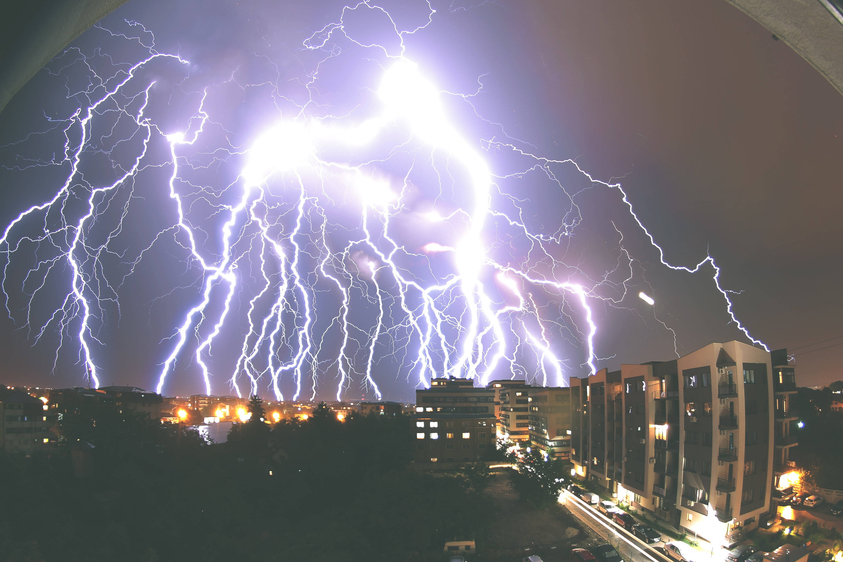 暴風 桌布 壁紙 — 巨大的閃電照亮了暴風雨夜晚的城市天際線，建築窗戶閃爍著光芒。