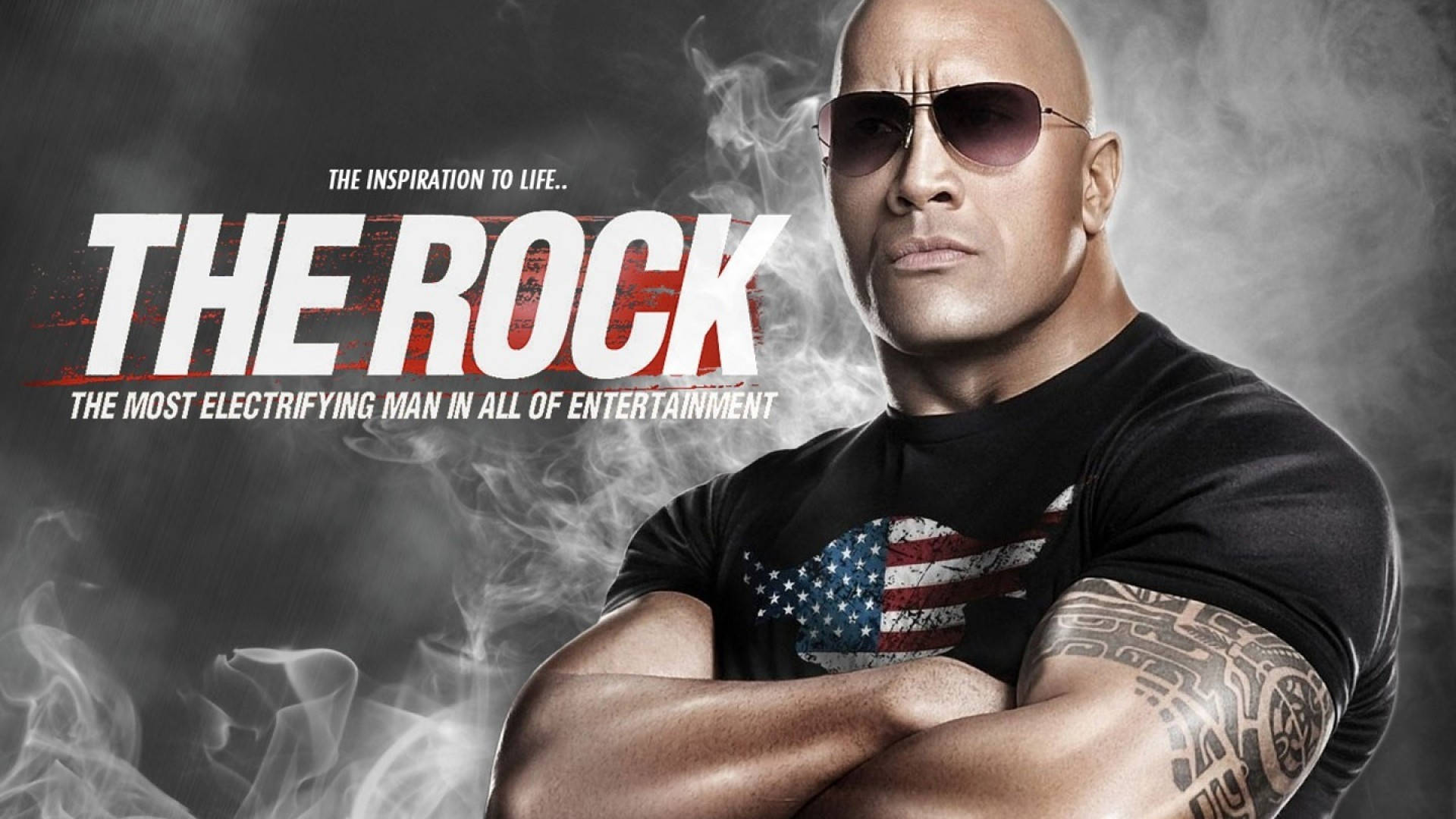 The Rock 桌布 壁紙 — 巨石強森自信地交叉雙臂站立，戴著太陽眼鏡和美國國旗T恤，背景是煙霧灰。