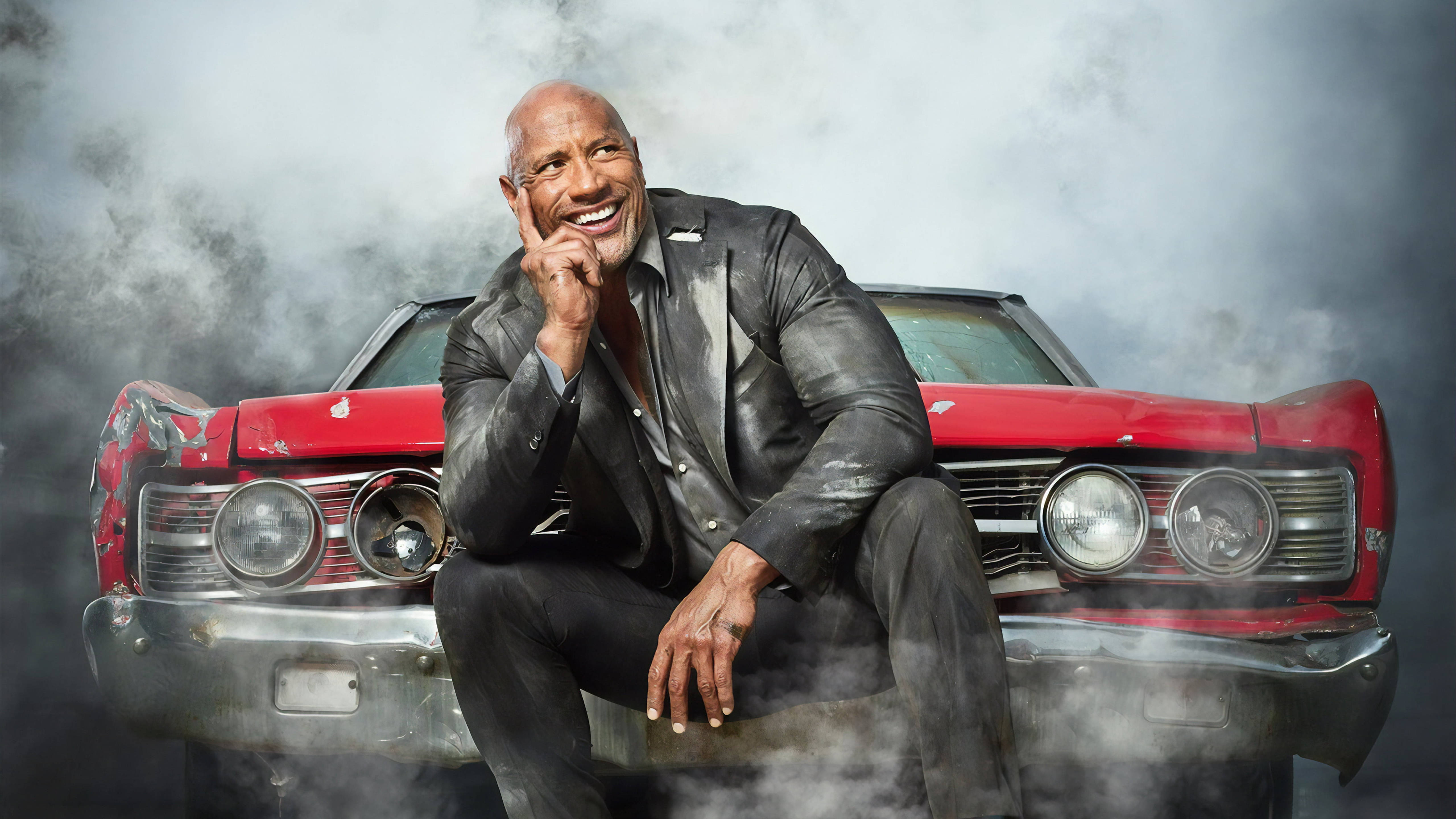 Dwayne 桌布 壁紙 — 巨石強森自信地微笑，坐在一輛經典紅色肌肉車上，周圍環繞著戲劇性的煙霧。
