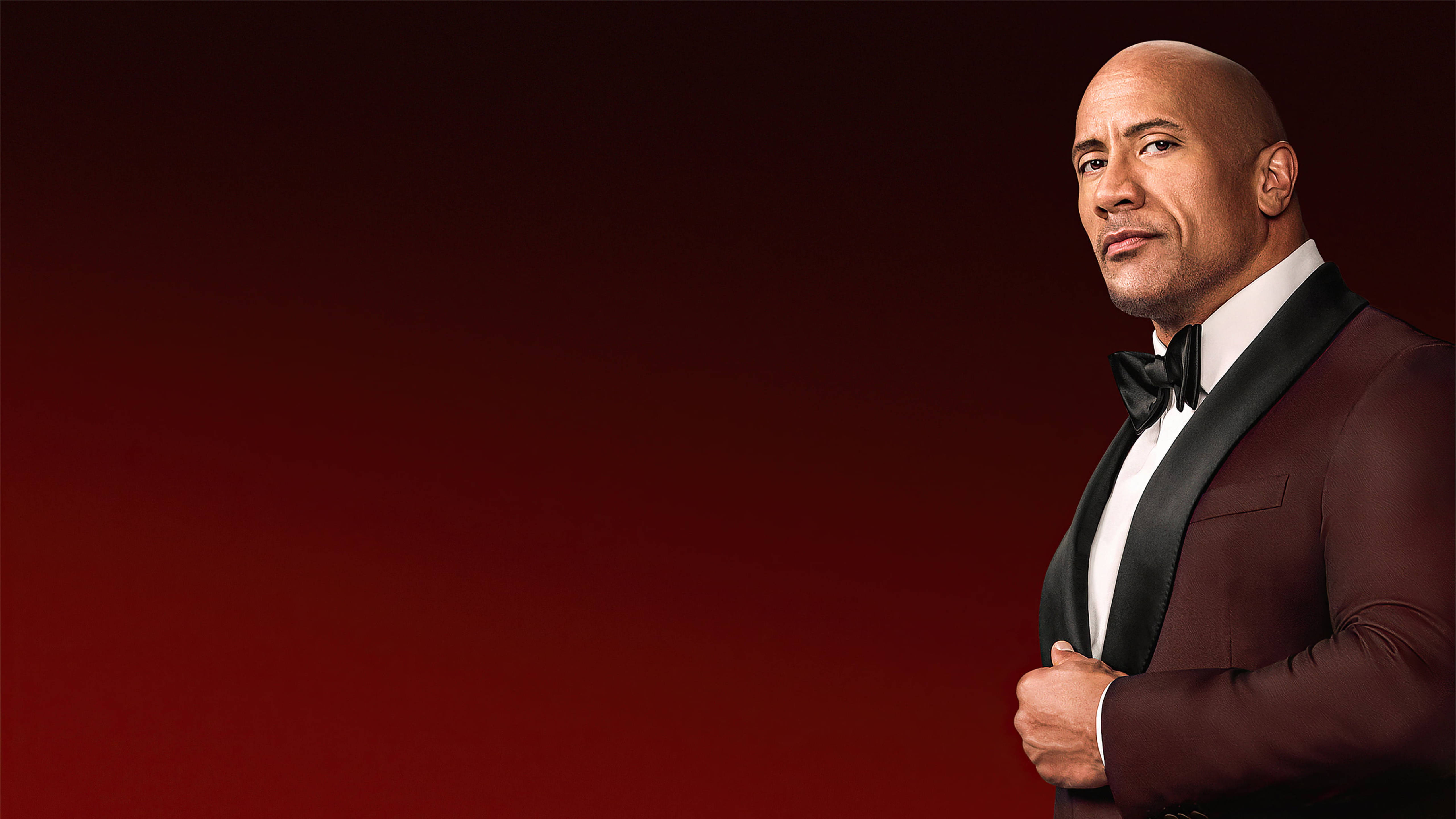 Dwayne 桌布 壁紙 — 巨石強森身穿栗色禮服搭配黑色蝴蝶結，自信地站在深紅色漸變背景前。