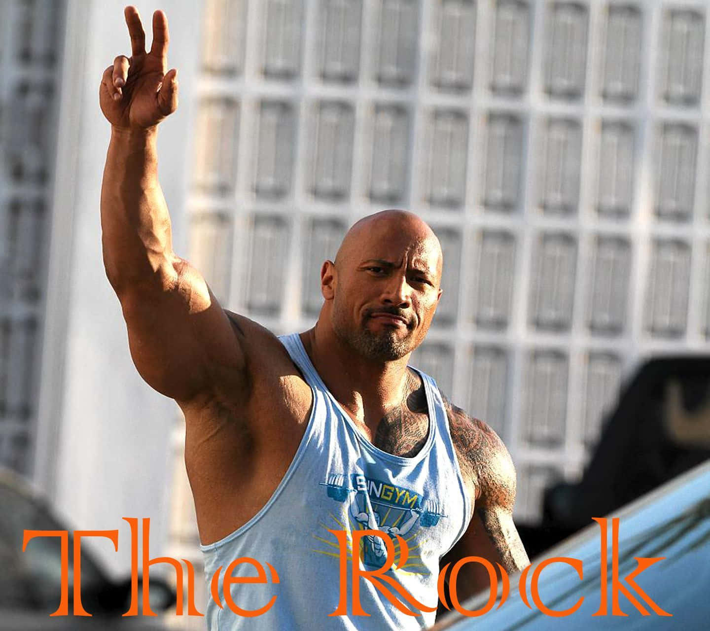 The Rock 桌布 壁紙 — 巨石強森身穿淺藍色背心，肌肉發達的手臂舉起做出和平手勢，背景是現代建築。