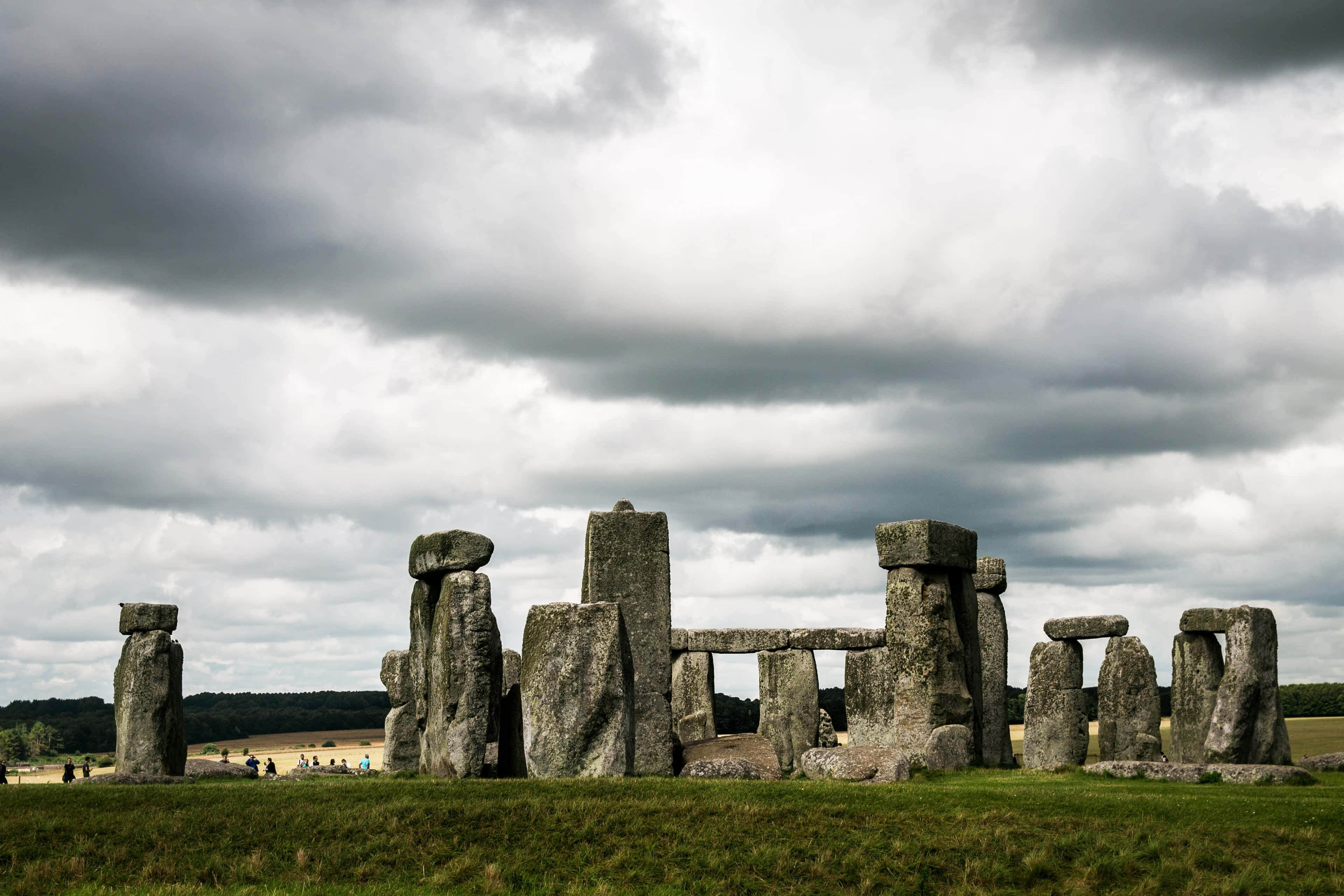 England 桌布 壁紙 — 巨石陣的古老立石在戲劇性的多雲天空下，莊嚴地聳立在草地上。