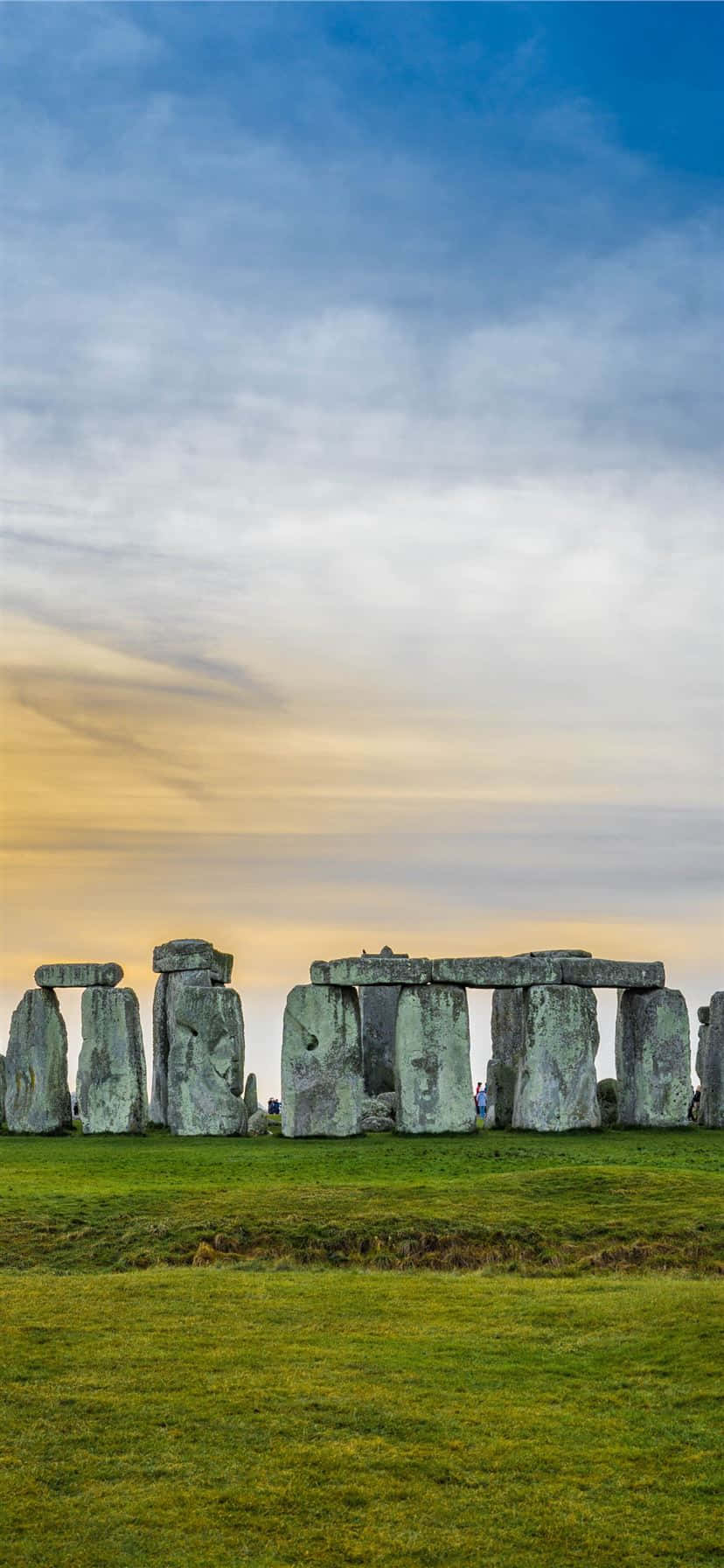 England 桌布 壁紙 — 巨石陣的古老立石在翠綠田野上，襯托著柔和的金色日落天空，雄偉地聳立。