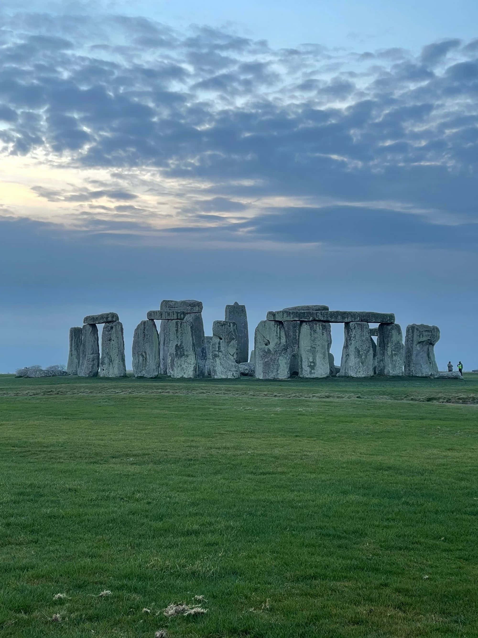 England 桌布 壁紙 — 巨石陣的古老立石在陰鬱的暮色天空下，從廣闊的綠色田野中莊嚴地升起。