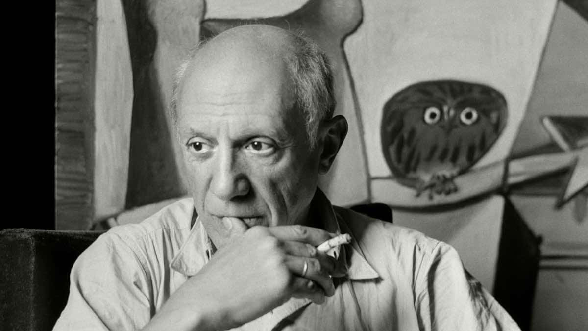 Picasso 桌布 壁紙 — 巴勃羅·畢卡索坐在他的工作室裡，手持香菸，身後有一幅大型黑白貓頭鷹畫作。