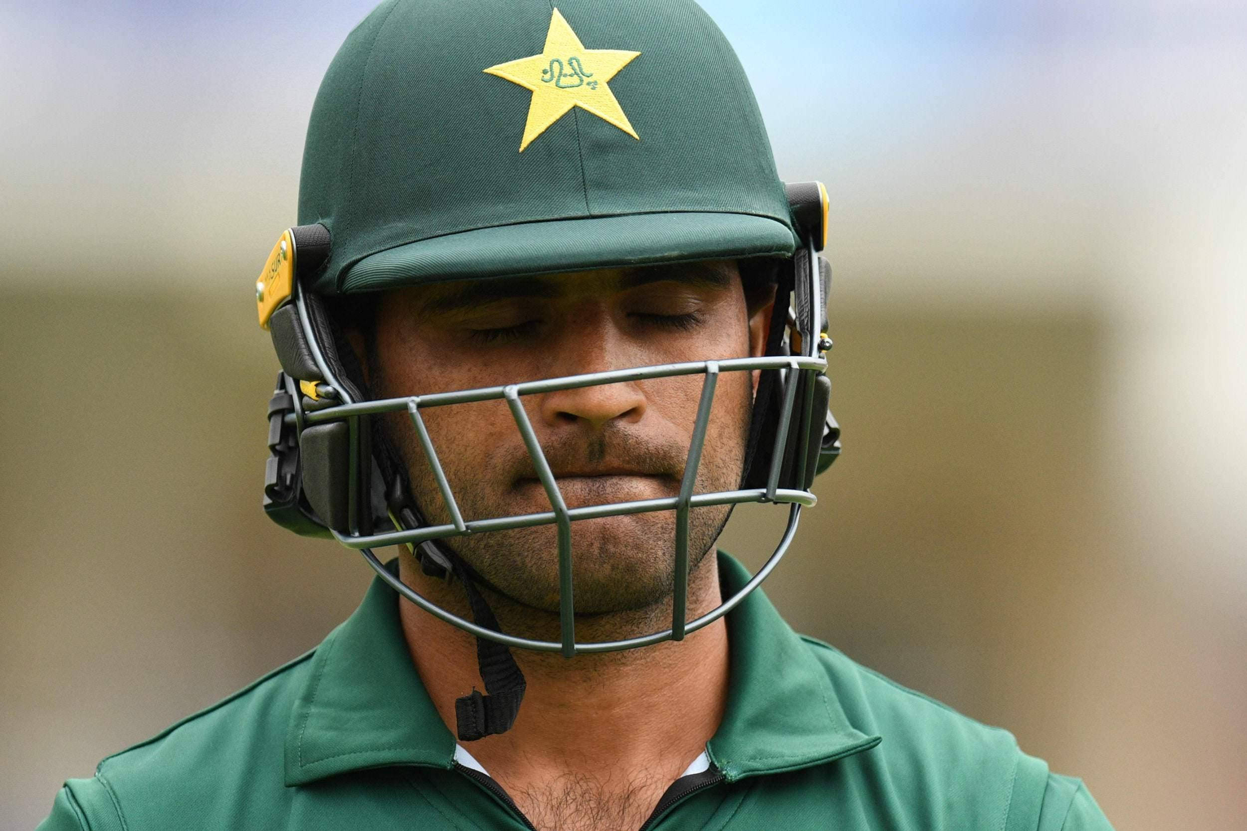 Fakhar Zaman 桌布 壁紙 — 巴基斯坦板球運動員的近照，閉上眼睛，戴著帶有黃色星星的綠色頭盔。