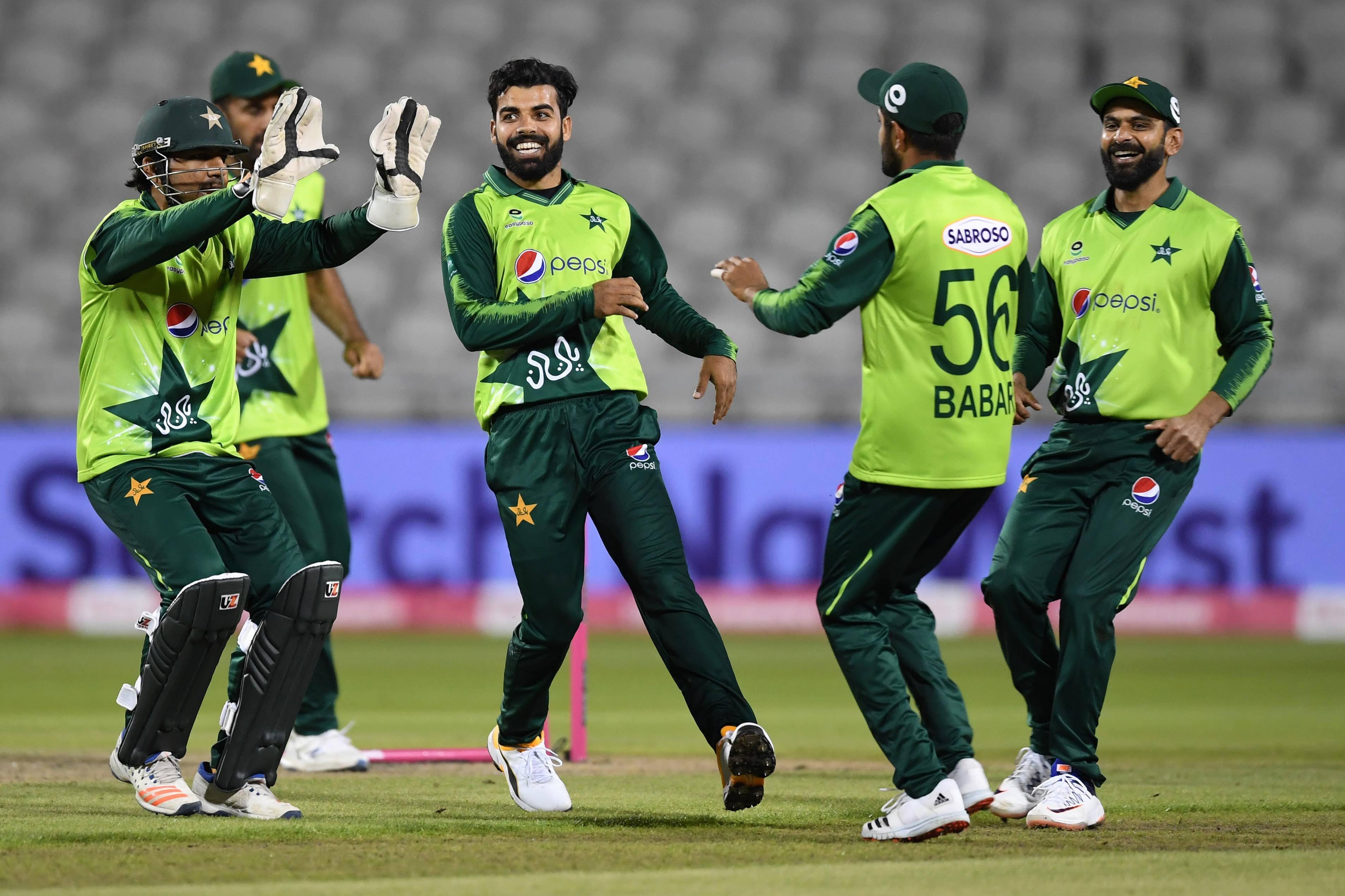 Pakistan Cricket 桌布 壁紙 — 巴基斯坦板球運動員身穿綠色制服，在球場燈光下的草地上熱情慶祝。